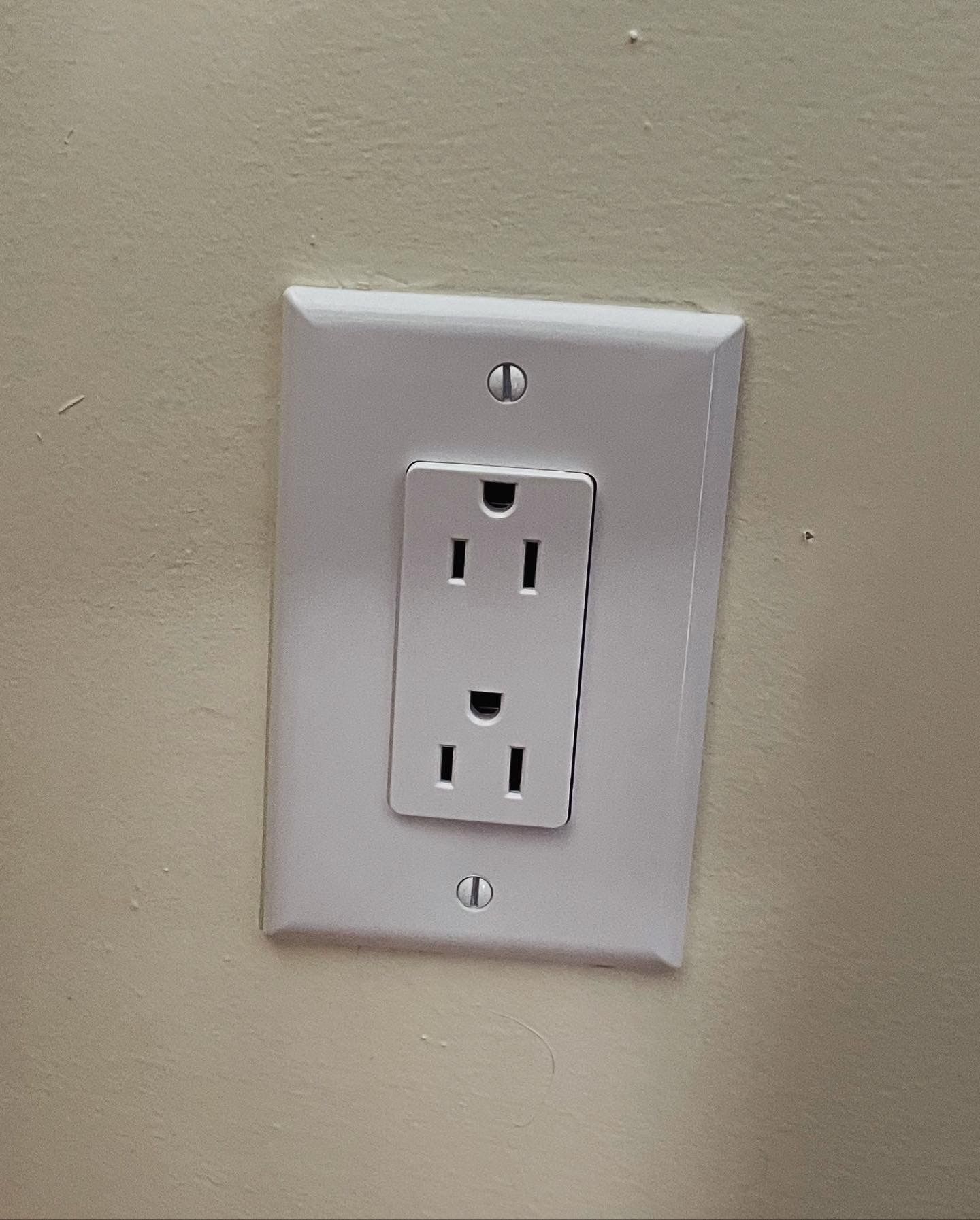 A white electrical outlet on a white wall