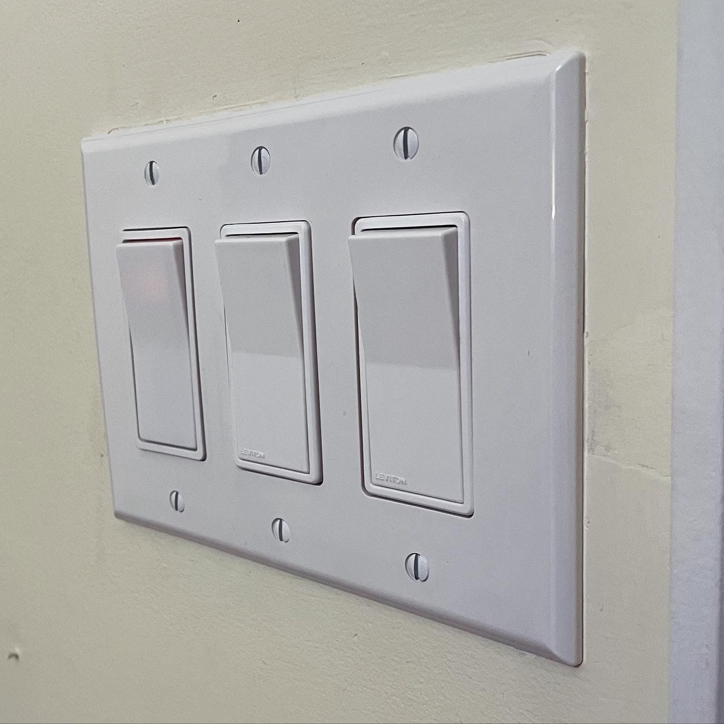 Three white light switches are mounted on a wall.