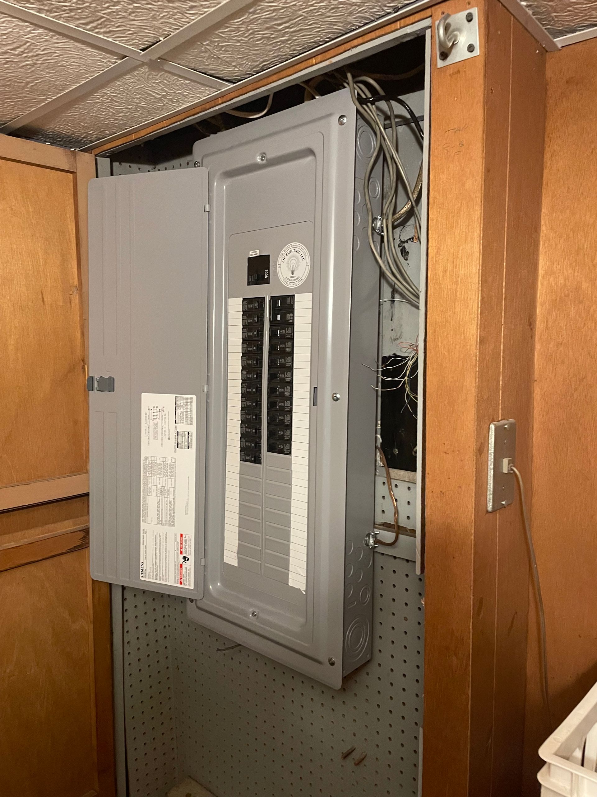 A electrical box is sitting inside of a wooden cabinet.
