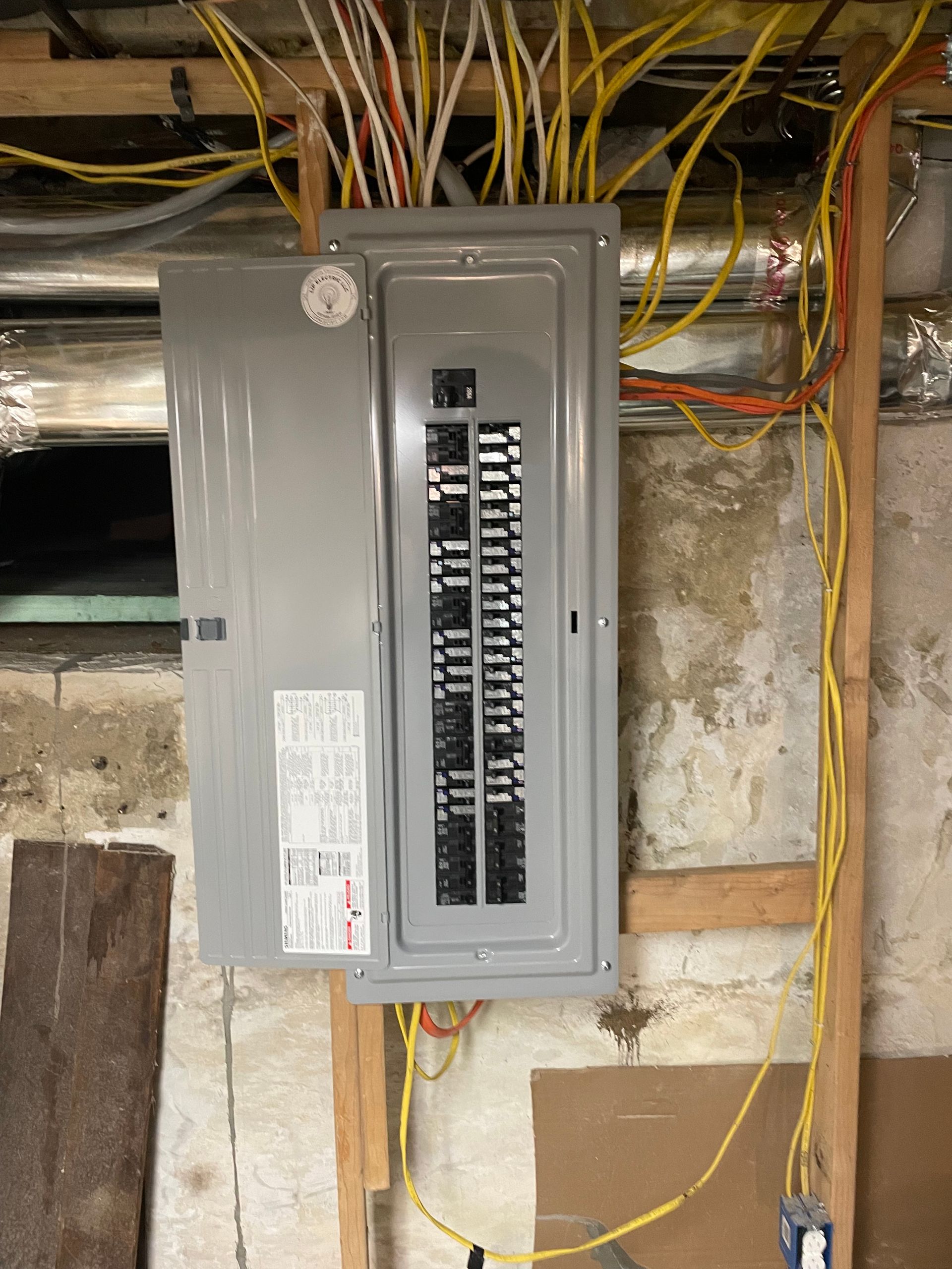 An electrical box is hanging on a wall in a basement.