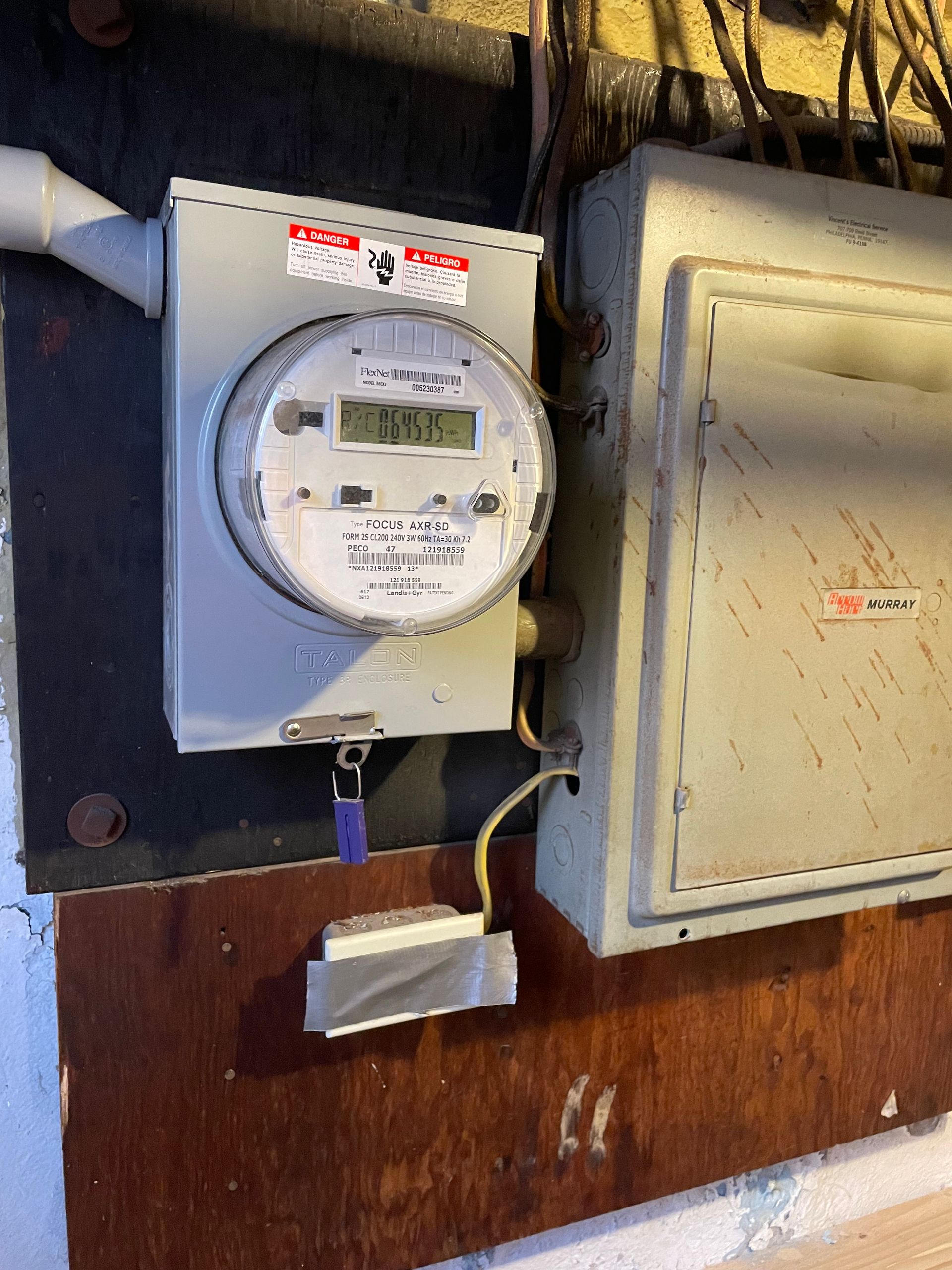 A meter is hanging on a wall next to a box.