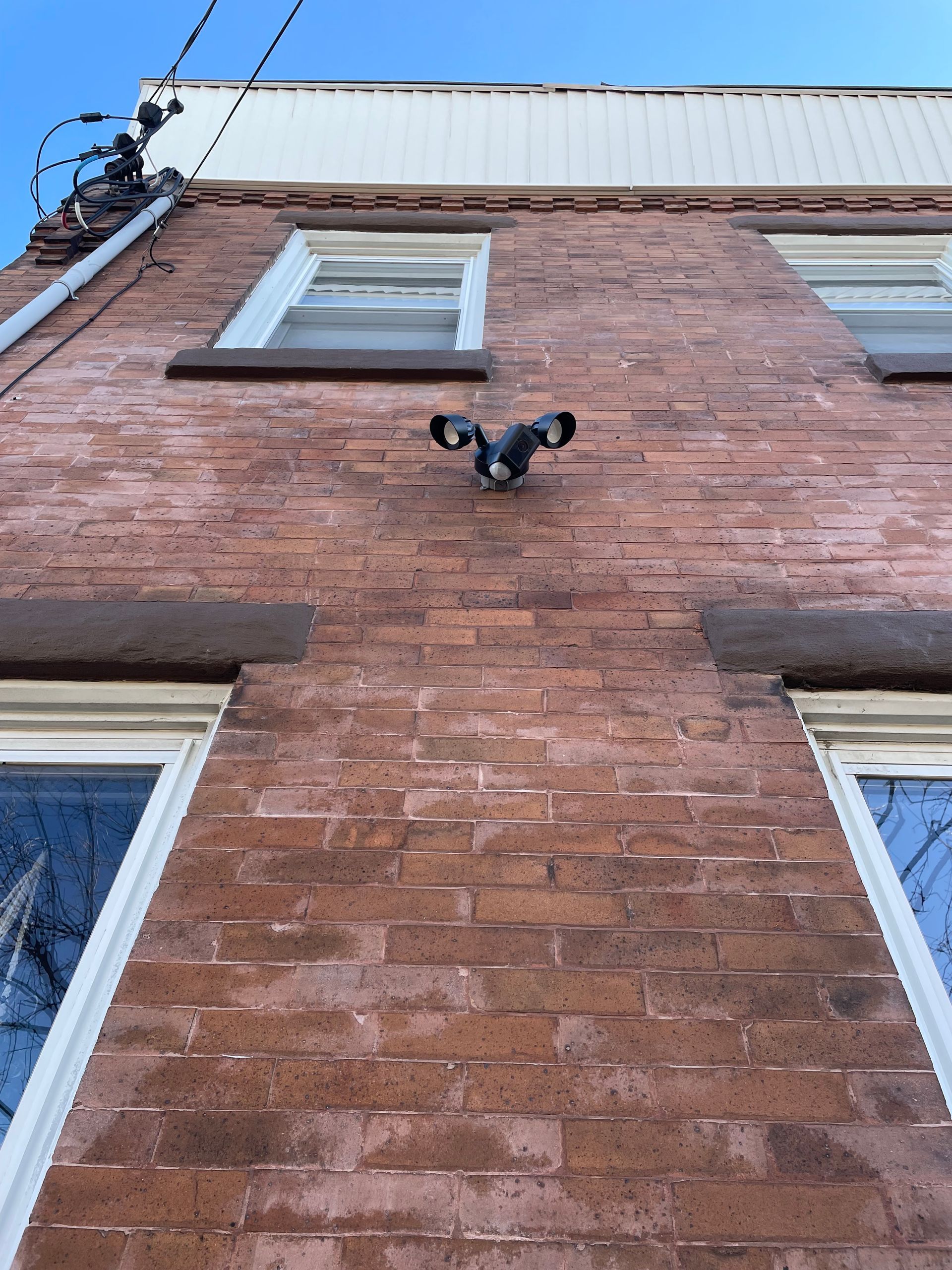 Looking up at a brick building with a bird on top of it.