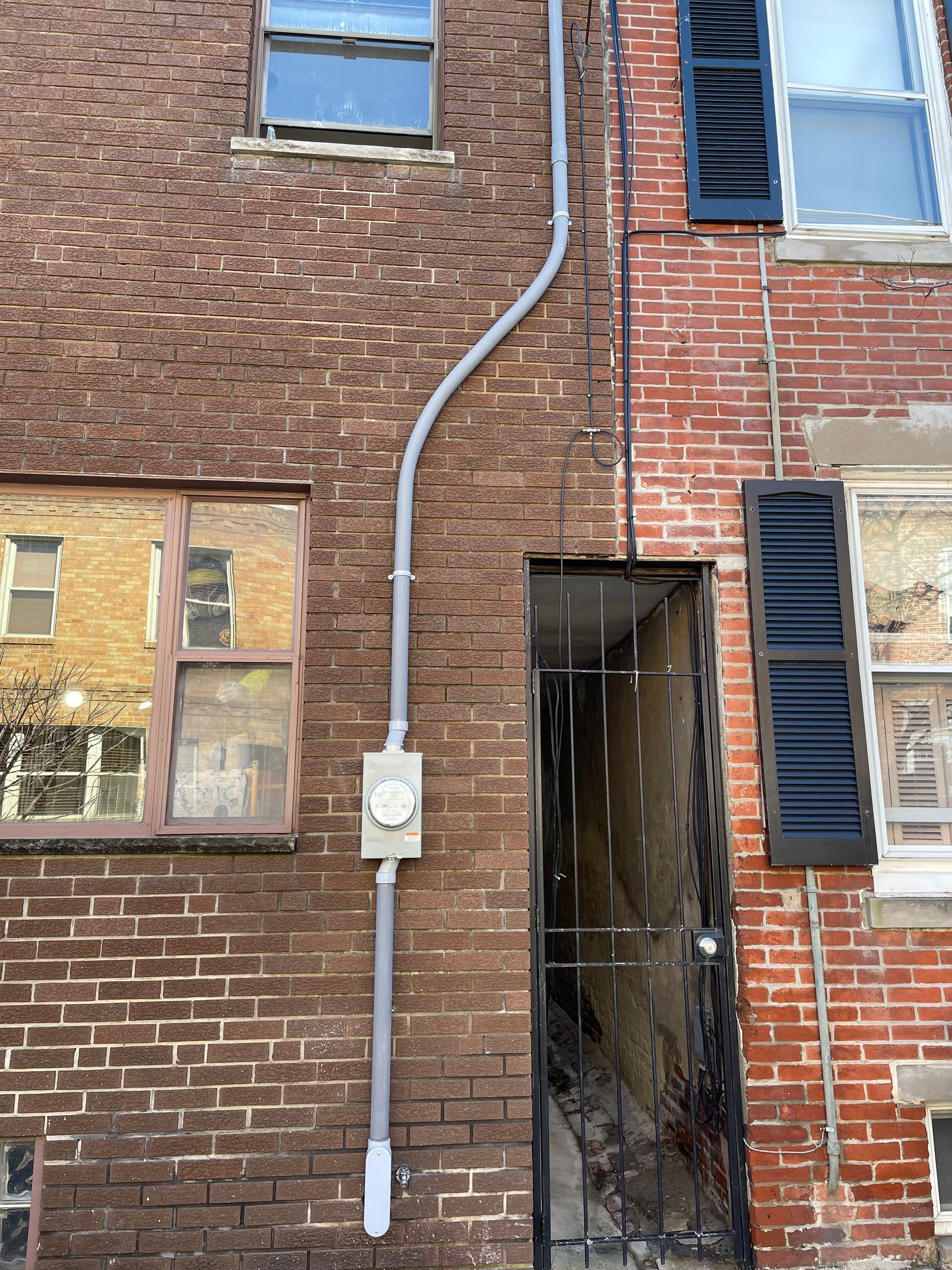 A brick building with a white pipe hanging from the side of it.