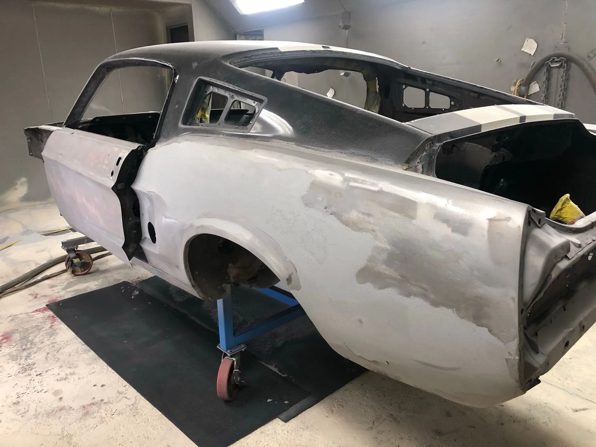 Partially restored classic car body, showing primer and bodywork.