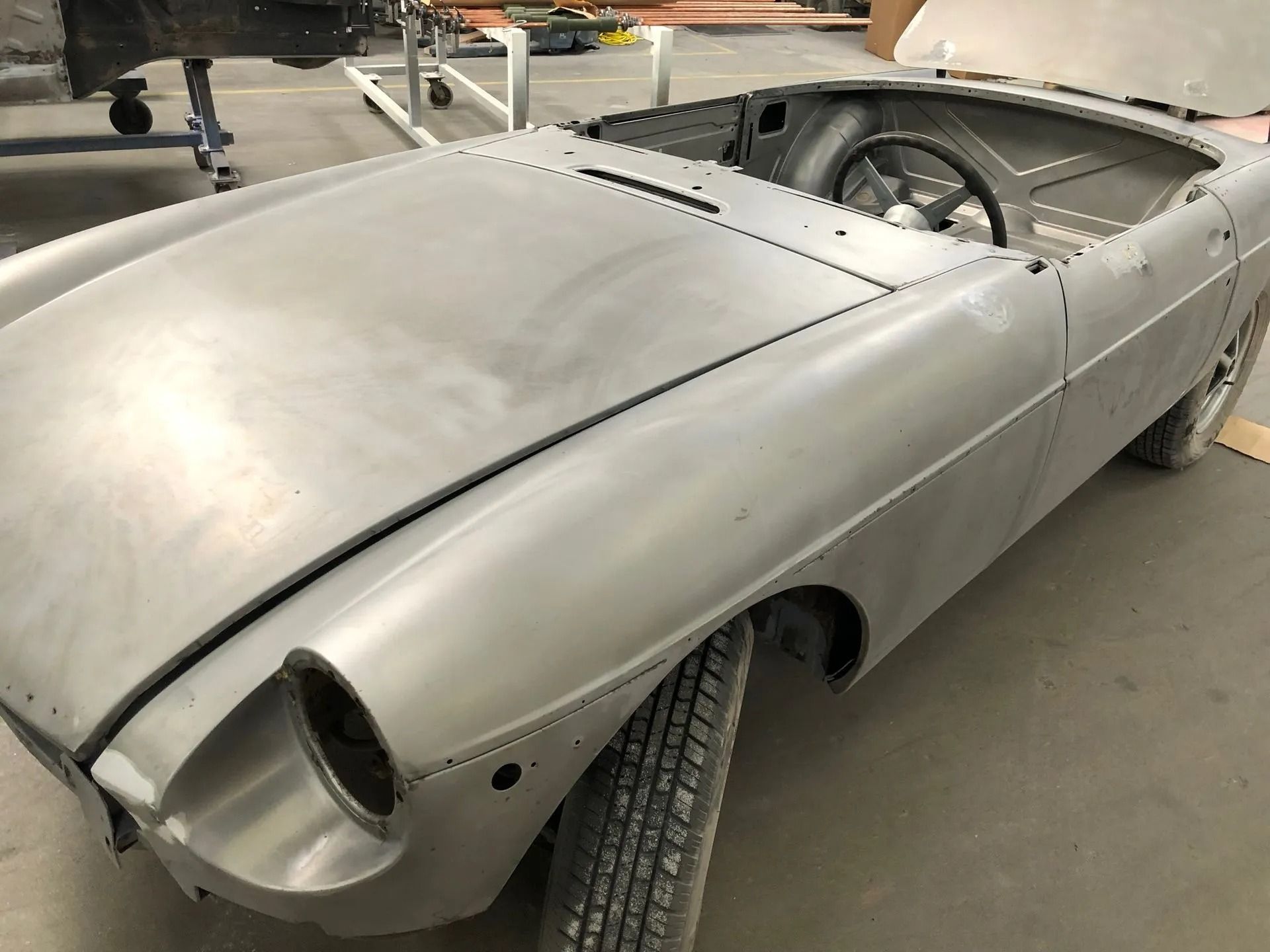 Bare metal classic convertible car in a workshop.