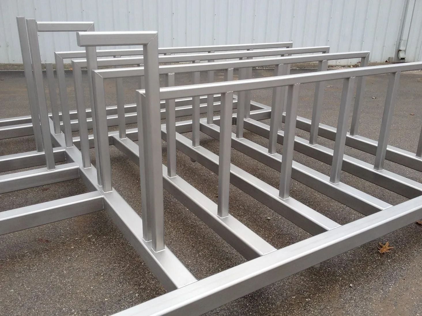 Metal bicycle rack, silver frame, rectangular design with vertical bars for bike placement.