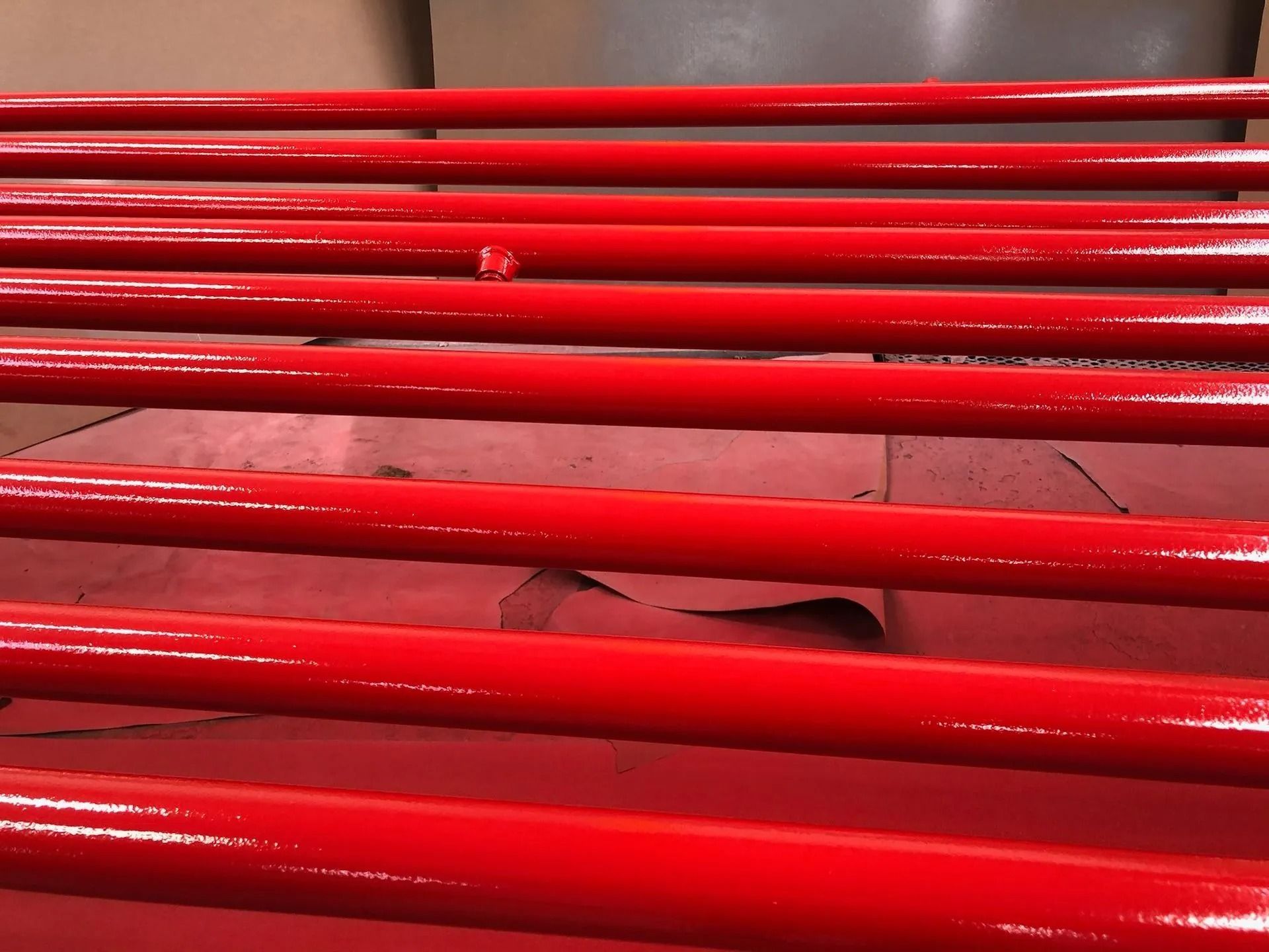 Bright red painted metal bars, possibly railings, arranged horizontally.