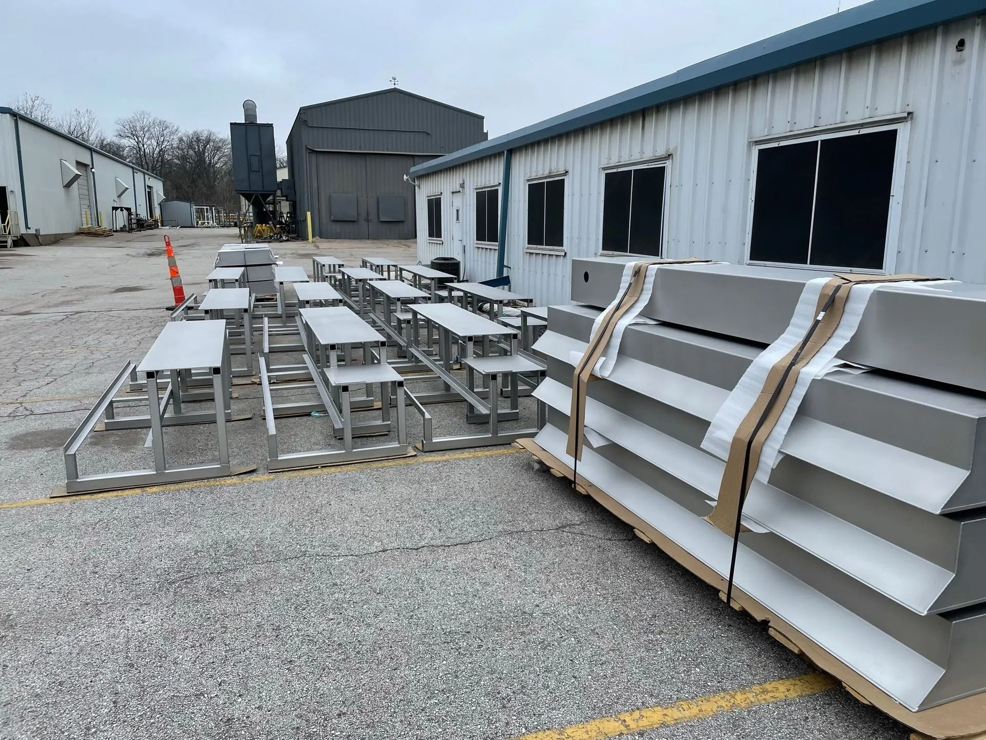 Outdoor metal bleachers and packaged seating in front of a white building with blacked-out windows.