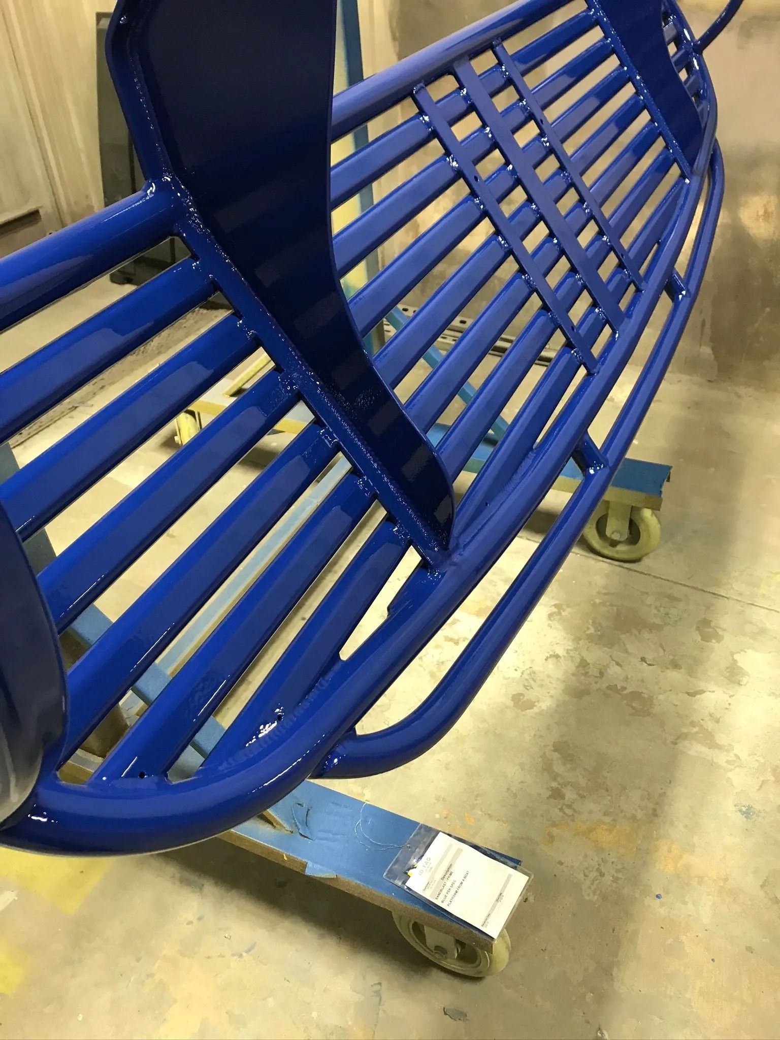 Blue metal bench frame on a rolling cart in a workshop setting.
