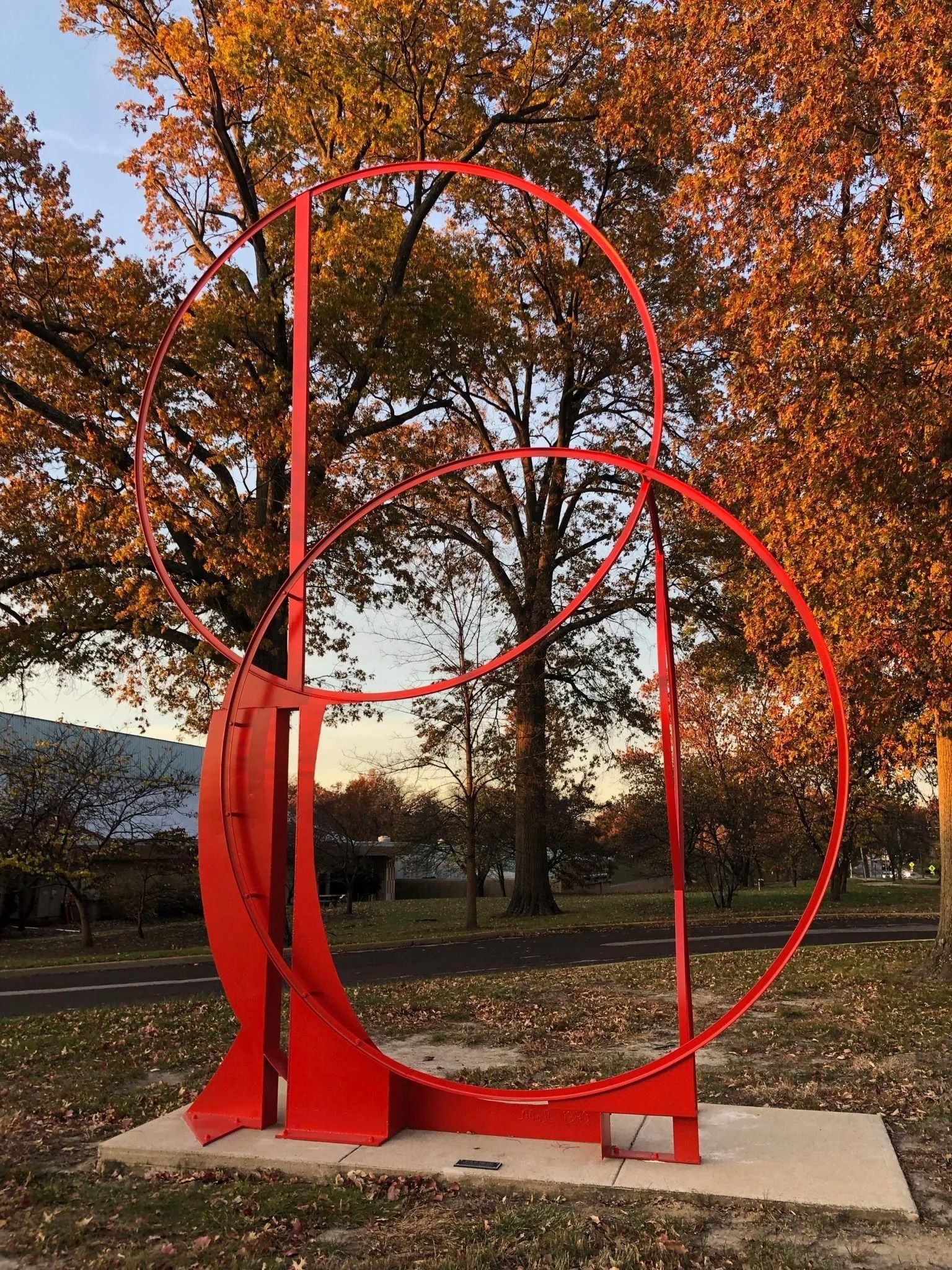 Red geometric outdoor sculpture against autumn trees.