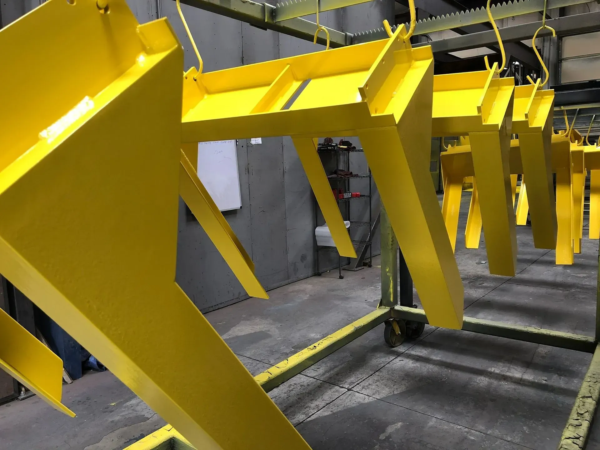 Yellow metal frames hanging on a conveyor line in an industrial setting.