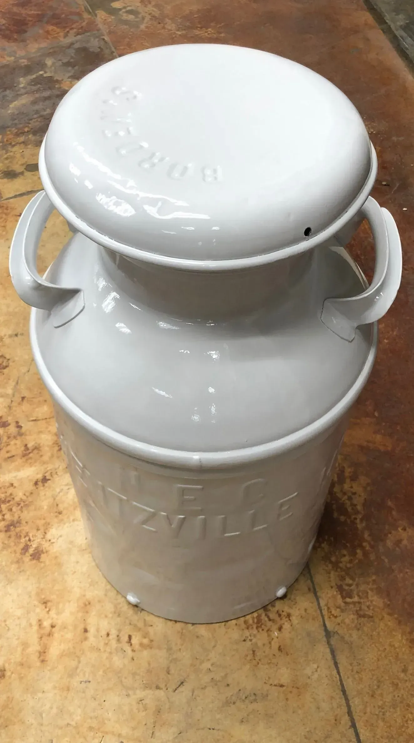 White milk can with a lid and handles.