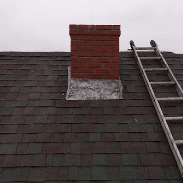 Rooftop chimney with red bricks and a ladder leaning against the shingles