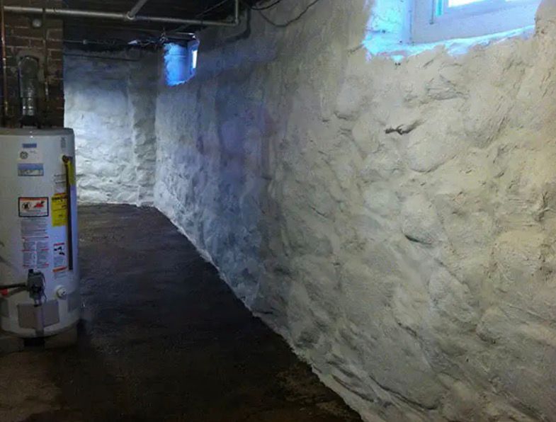 Dim basement corridor with rough white stone walls, dark floor, and a utility cabinet on the left.