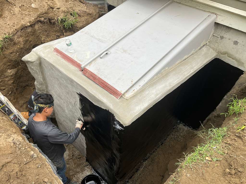 Worker inspecting a concrete underground structure with a white cover in an excavation site
