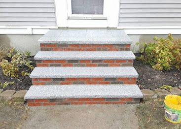 Concrete front steps with red brick accents leading to a white house entrance