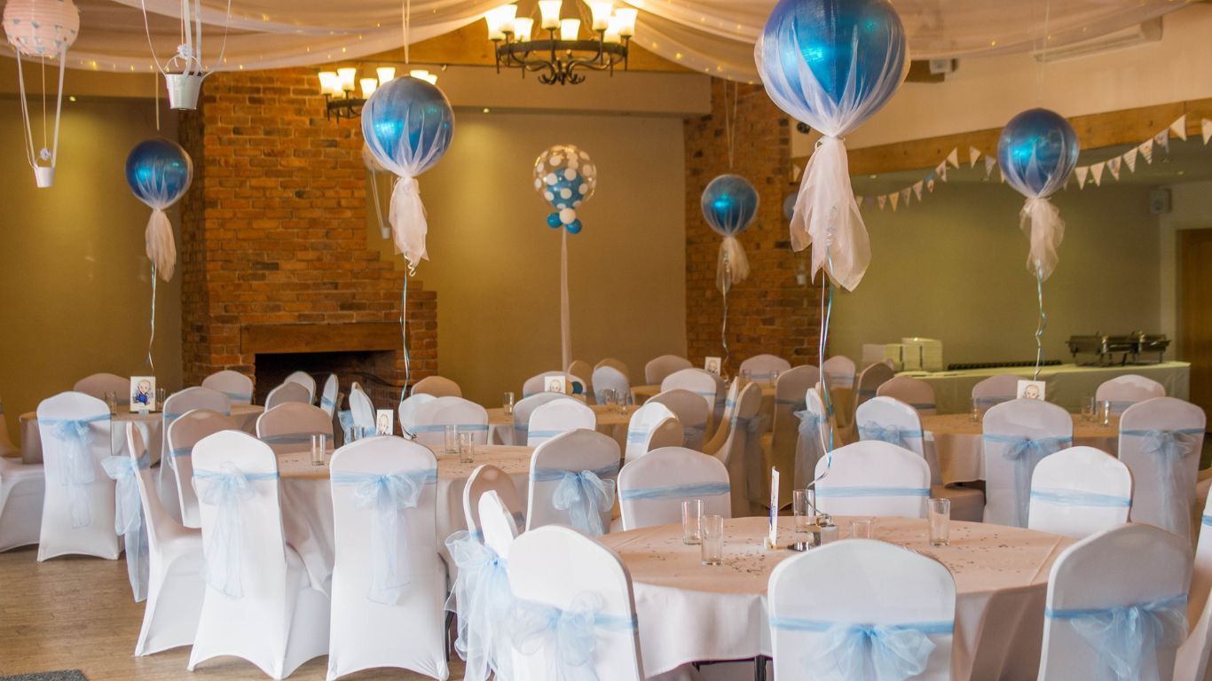 Wedding reception with decorated tables, balloons, and white and blue accents.