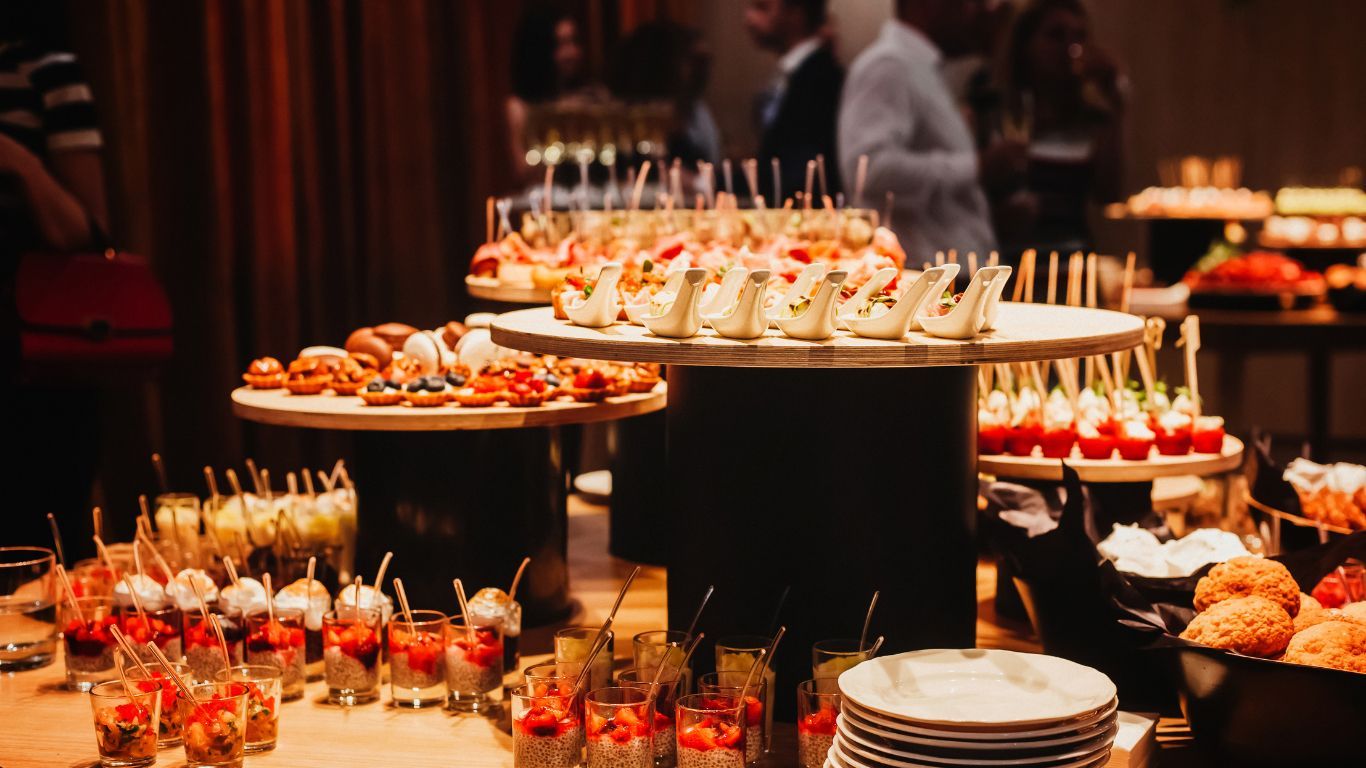 Buffet spread: hors d'oeuvres, desserts, and drinks on tiered tables at an event.