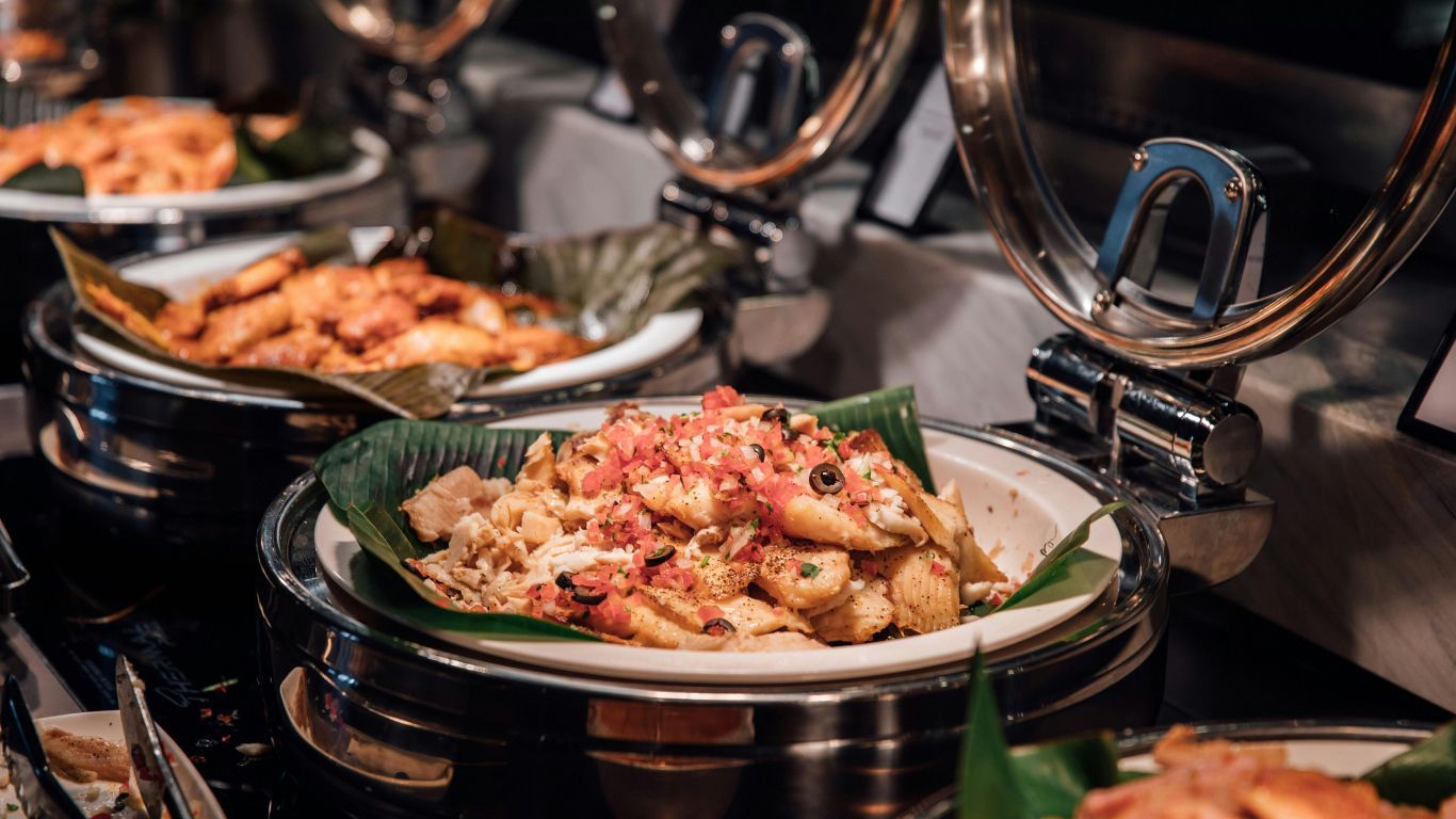 Buffet spread of various cooked dishes, including seafood, with silver serving dishes.