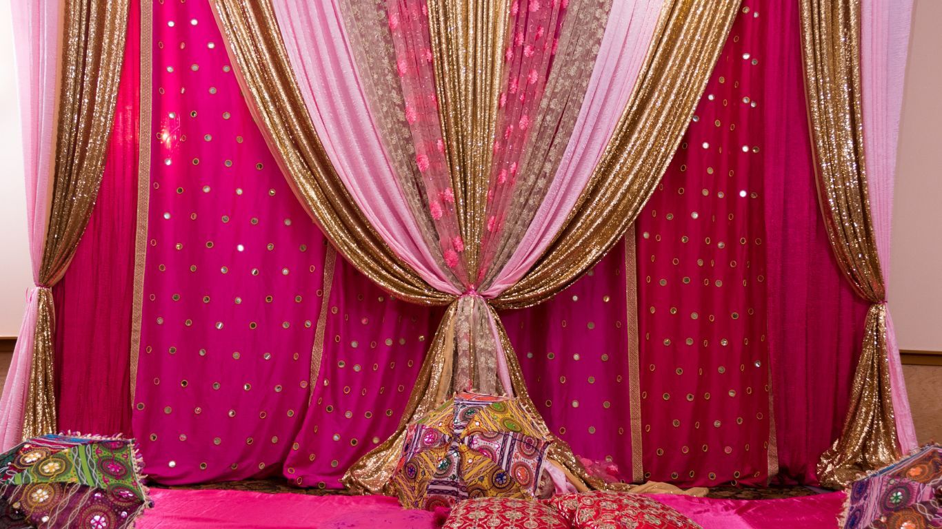Pink and gold fabric backdrop with pillows, for an event.
