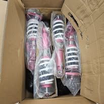 Pink and silver suspension struts inside a cardboard box.