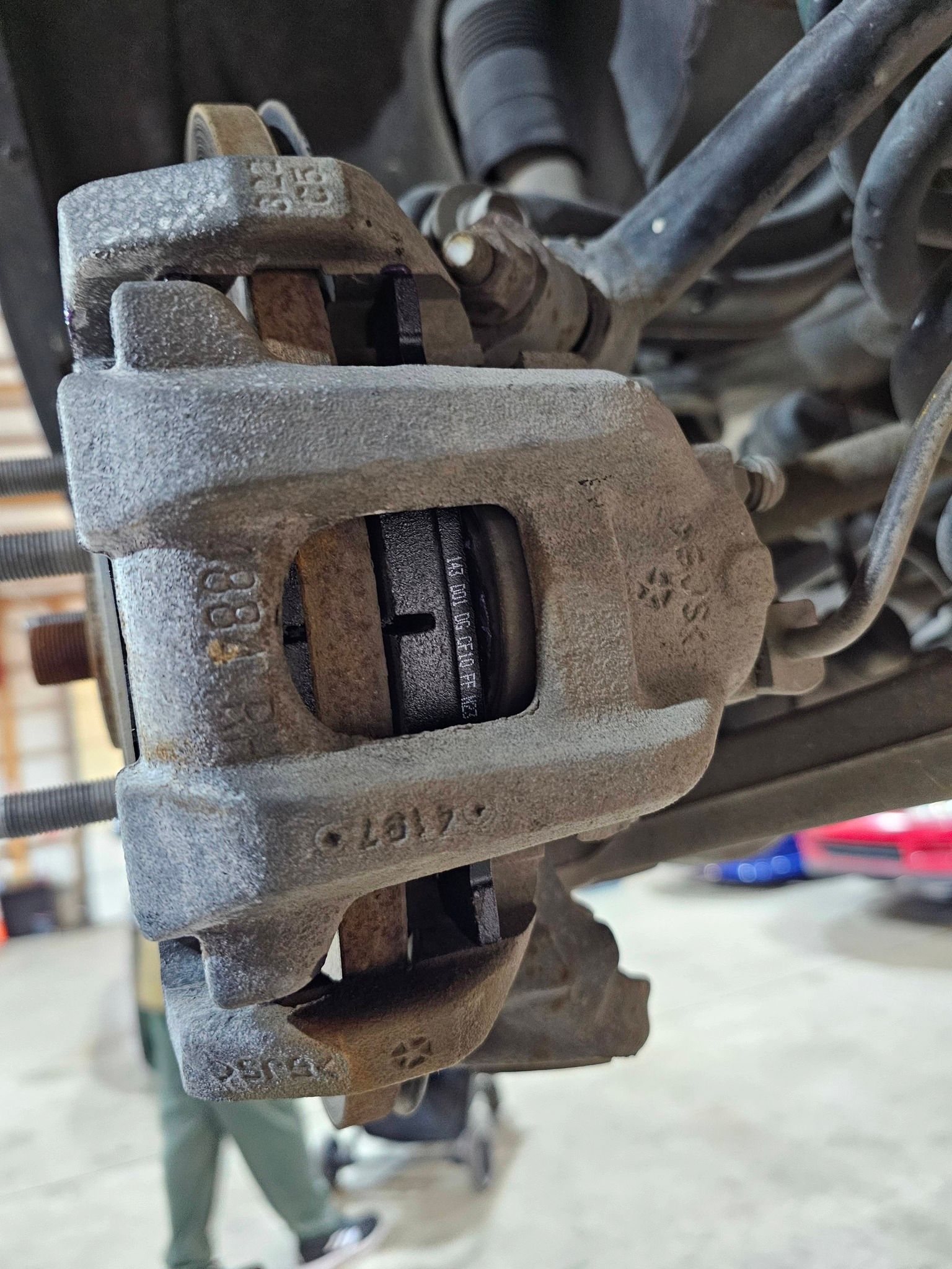 Car brake caliper with brake pads installed, viewed from the side.