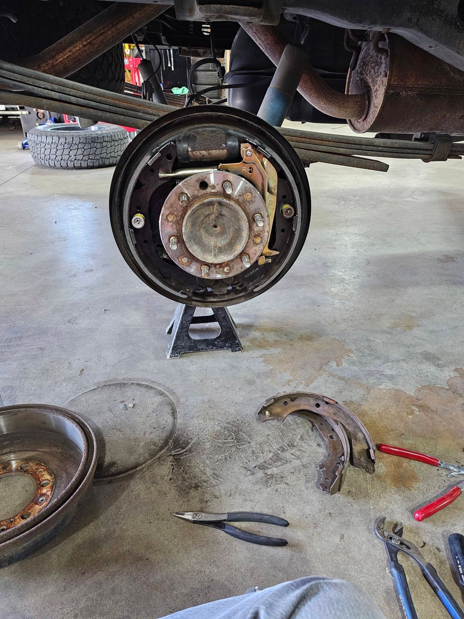 Truck's rear drum brake disassembled for maintenance in a garage.