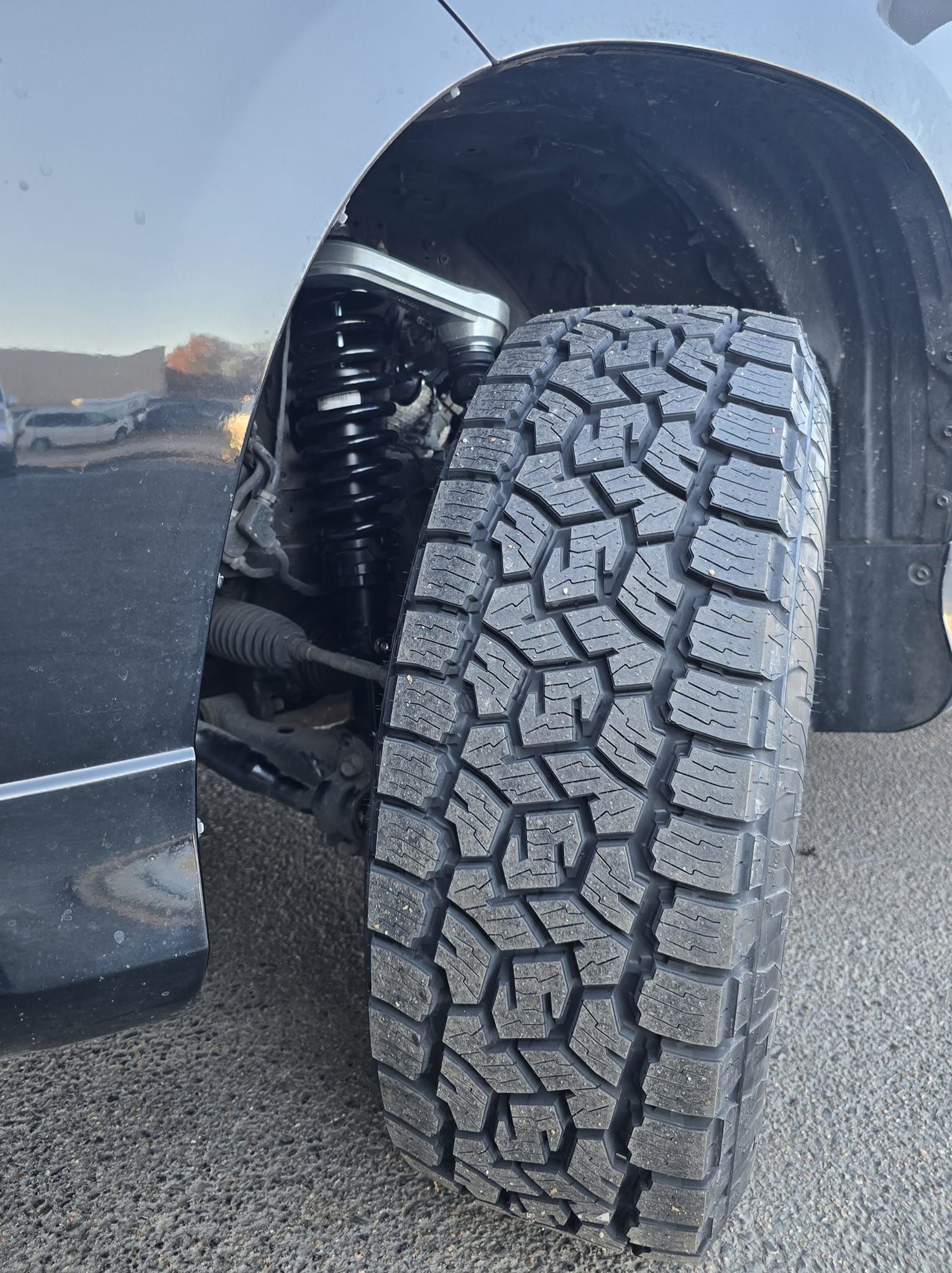 Black tire with a rugged tread pattern on a vehicle, viewed from the side.