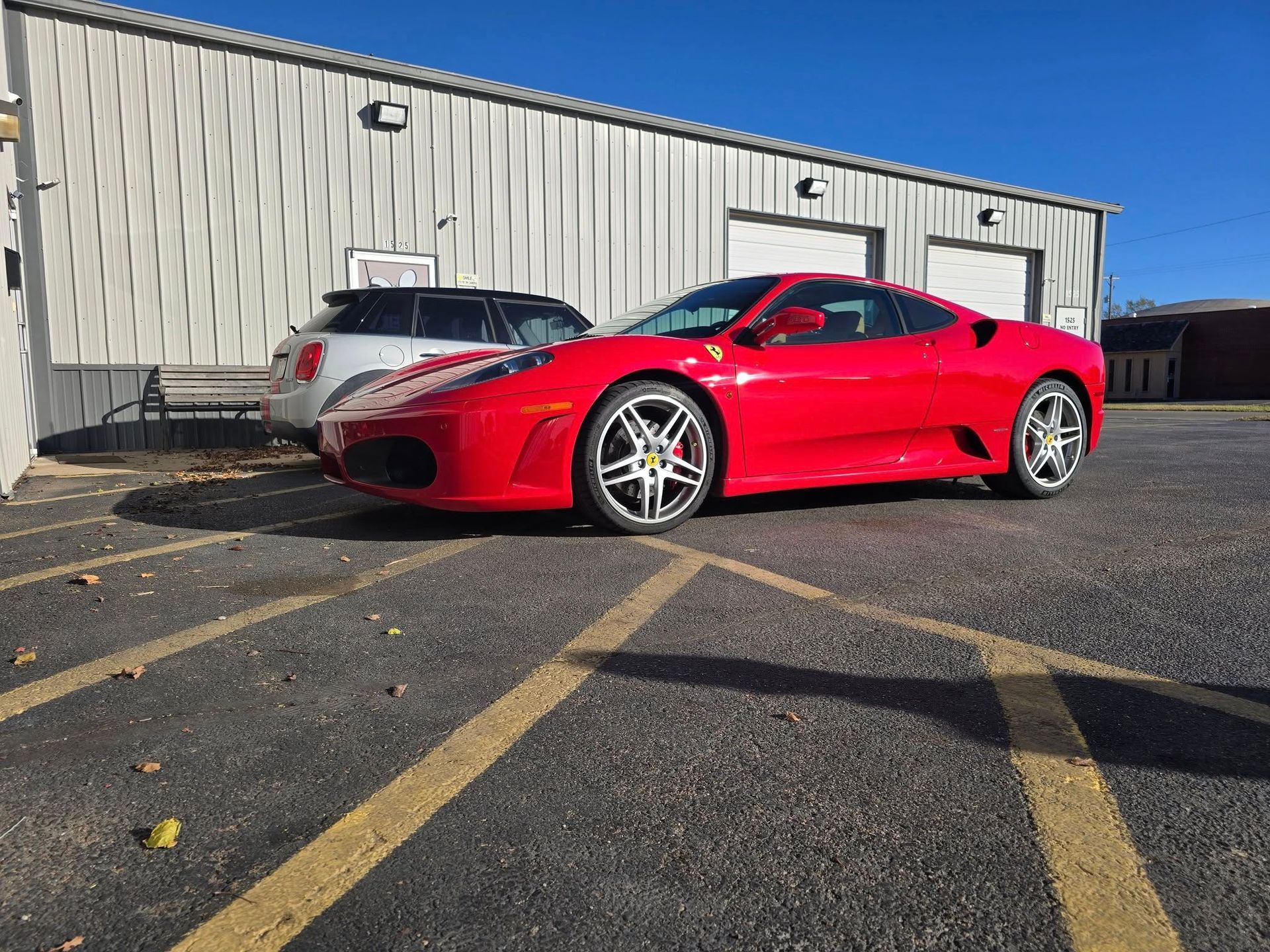 Red Ferrari parked in front of a white building on a sunny day.