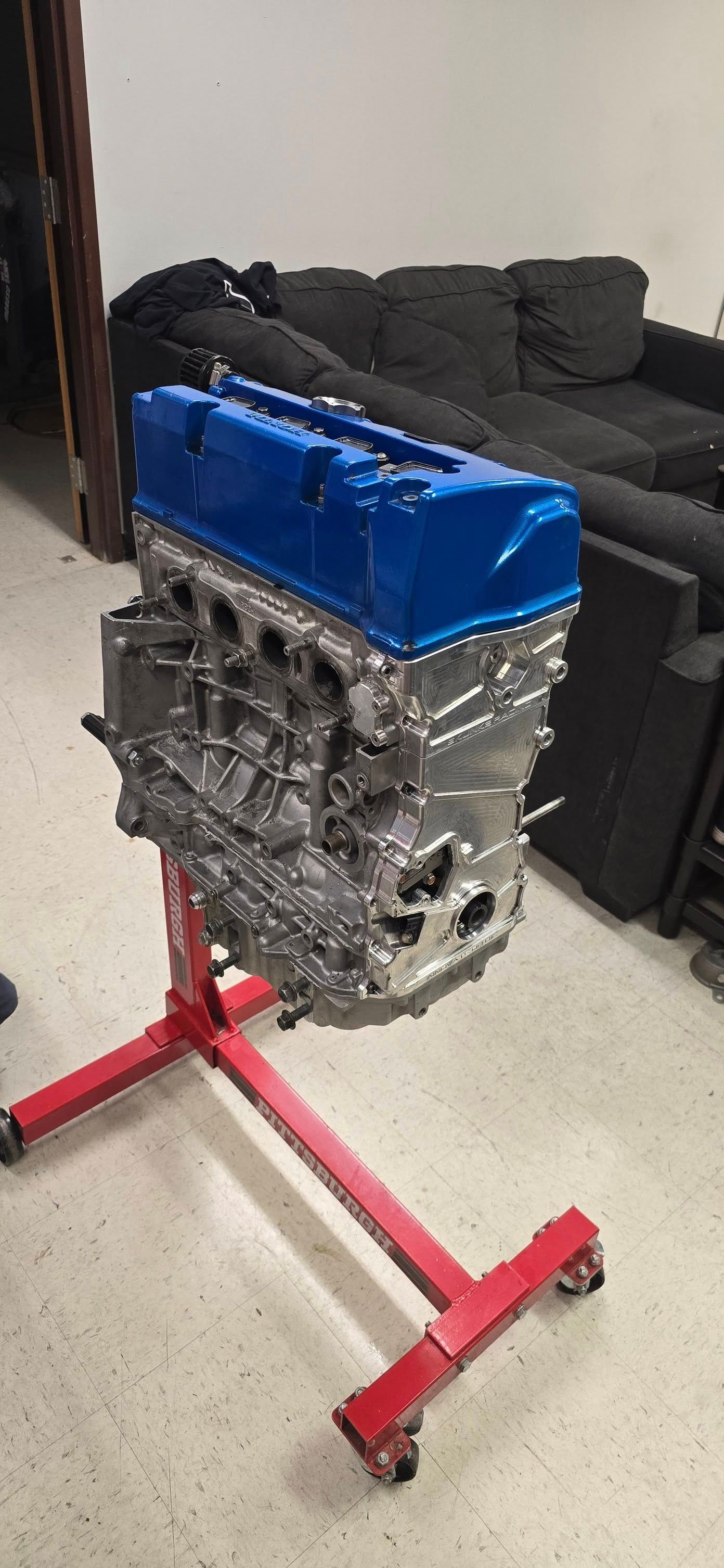 Engine on a red stand with a blue valve cover.