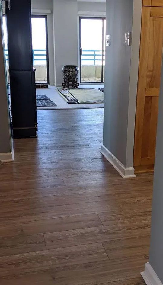 A hallway leading to a living room with hardwood floors and sliding glass doors.