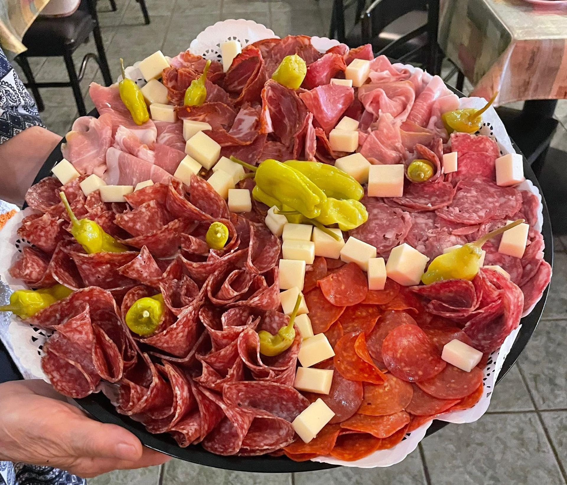 Charcuterie platter with assorted cured meats, cheeses, and green peppers on a white tray
