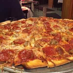 Large pepperoni pizza on a metal tray in a restaurant setting