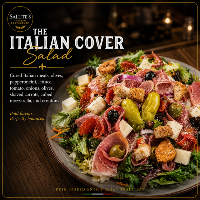 Colorful salad with greens, prosciutto, cheese cubes, olives, and cherry tomatoes on a gray plate