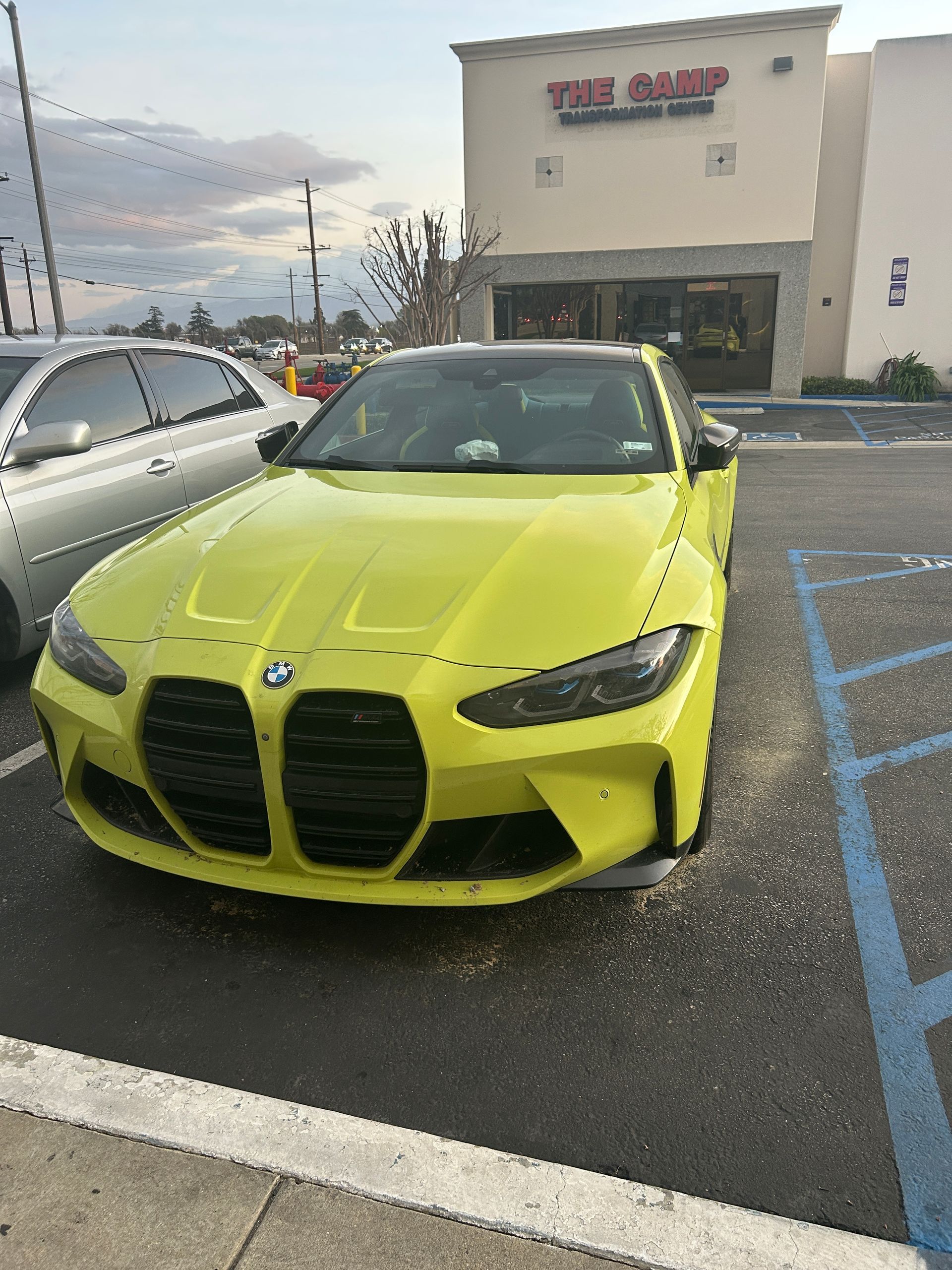 Bright yellow BMW parked in a shopping center lot near a store entrance