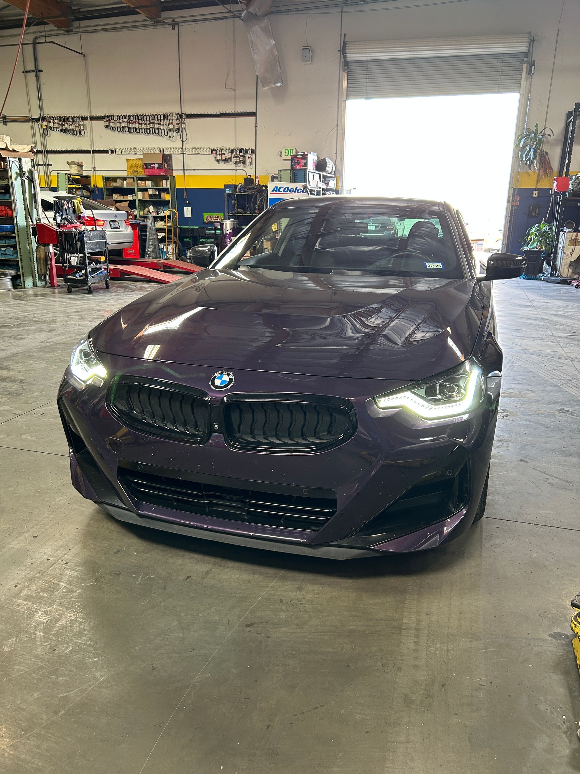 Dark BMW sedan parked inside an auto repair shop garage.
