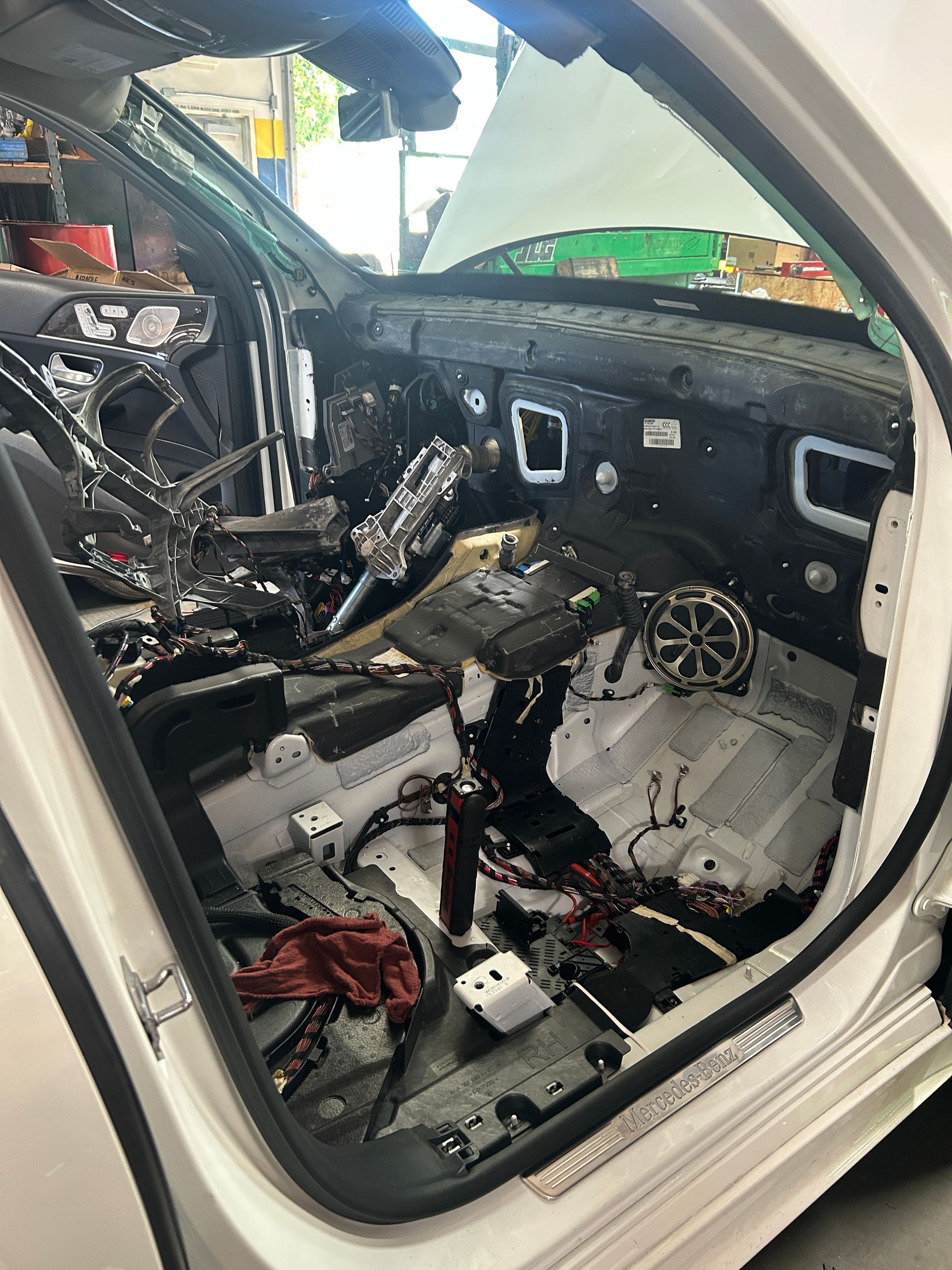 Stripped car interior with exposed wiring, missing dashboard and seats, viewed from the open door.