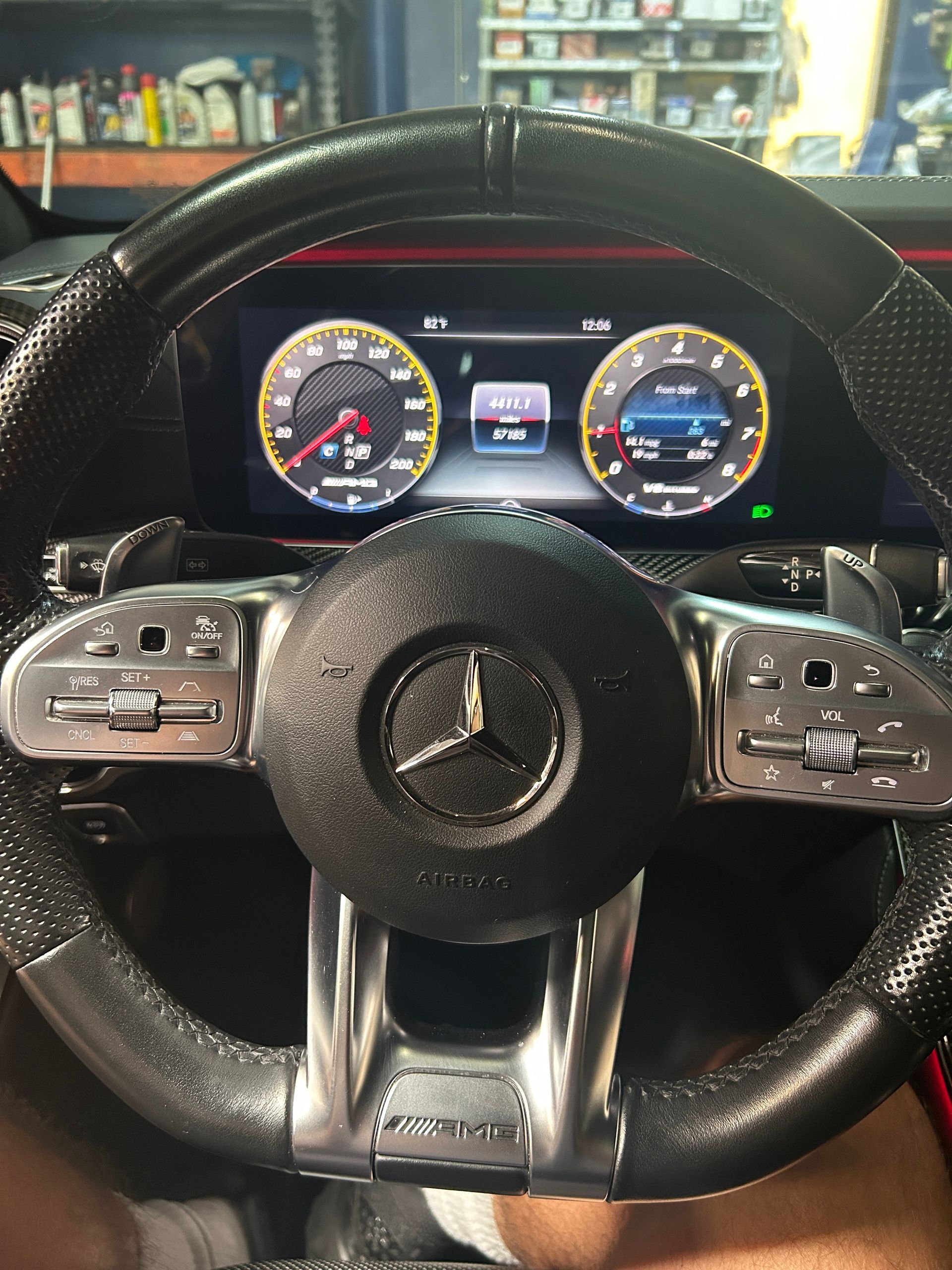 Mercedes steering wheel and digital dashboard with gauges lit in a garage or showroom