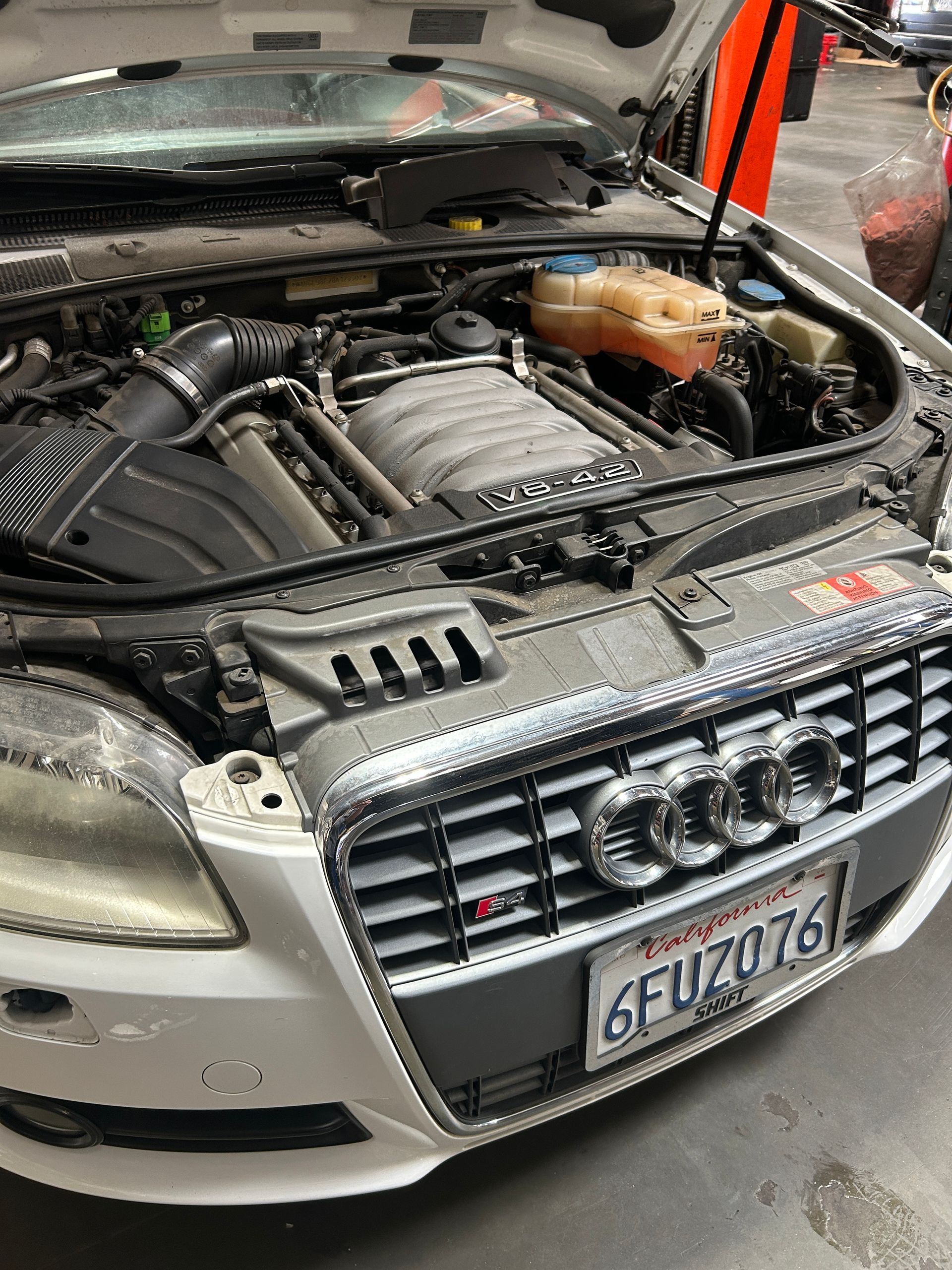 Audi sedan with hood open in a garage, revealing the engine bay.