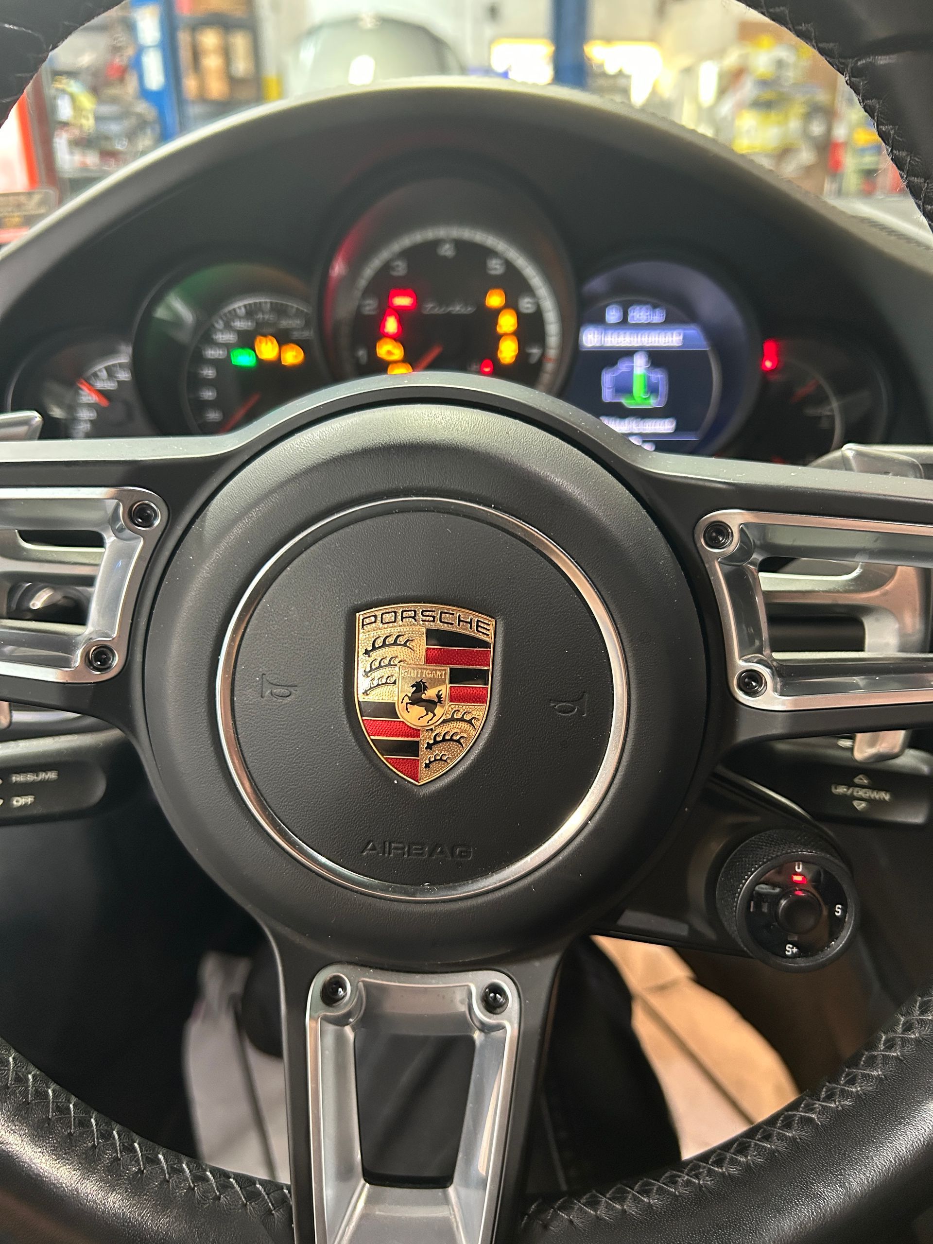 Porsche steering wheel and dashboard viewed from the driver’s seat inside a sports car