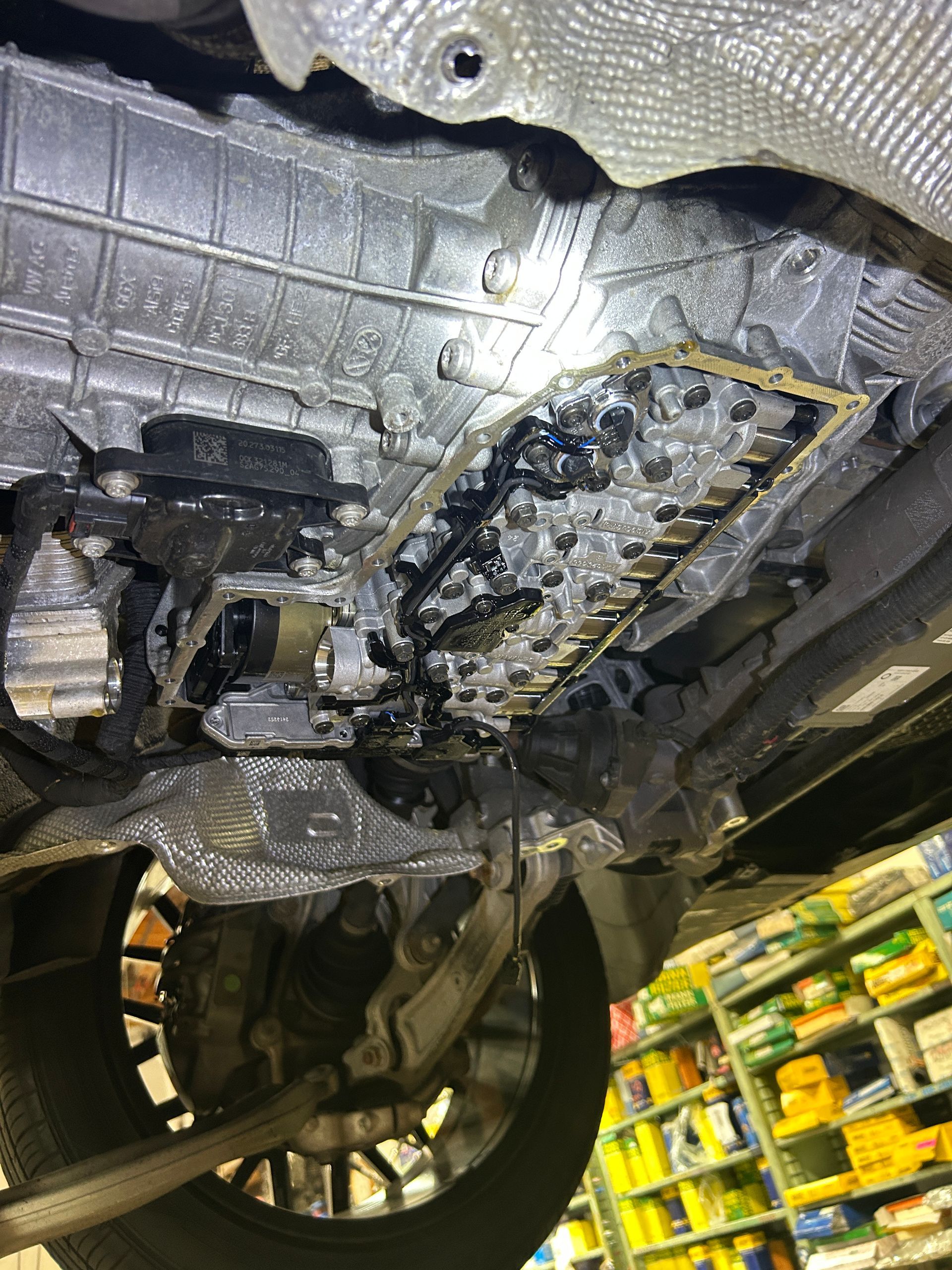 Undercarriage of a car on a lift, showing the transmission pan and exposed mechanical components.