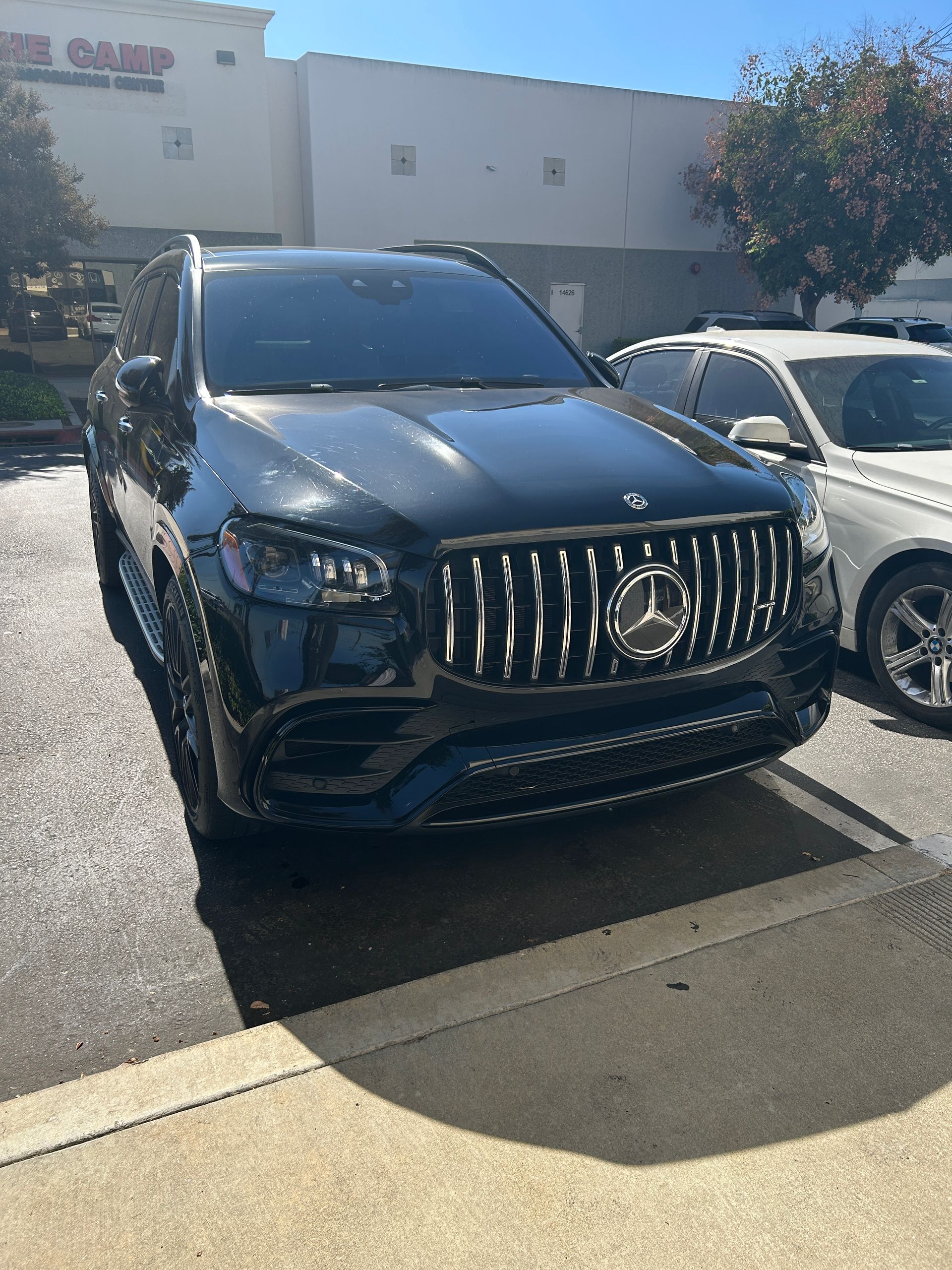 Black Mercedes SUV parked in front of a store on a sunny day