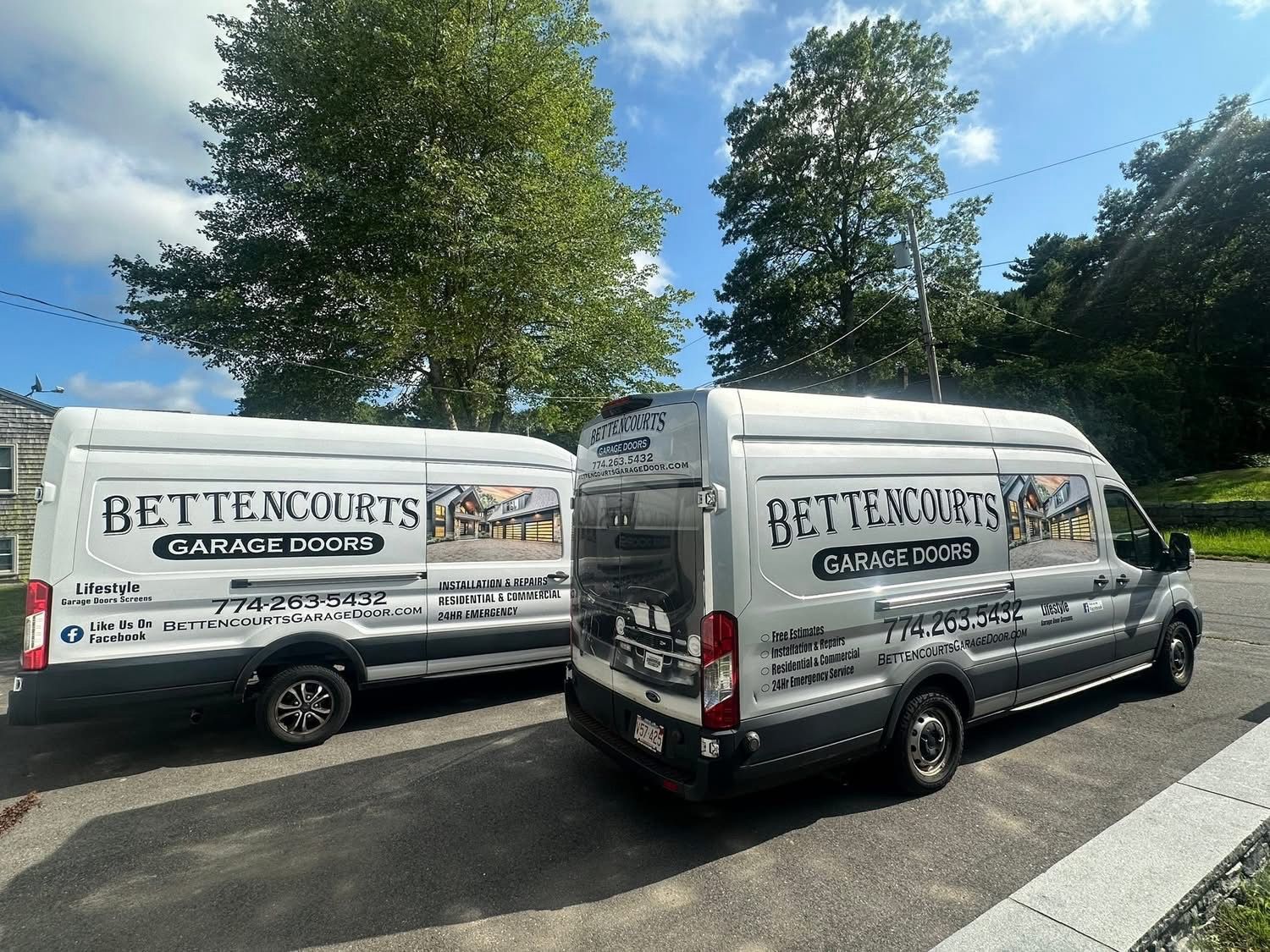 Two white vans are parked next to each other on the side of the road.
