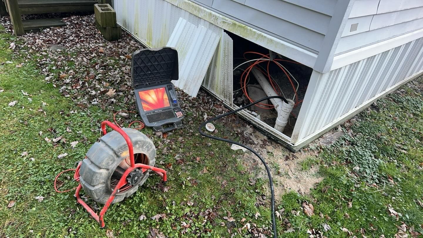A sewer camera and monitor set up outside a mobile home for a plumbing inspection of the under-skirting pipes.