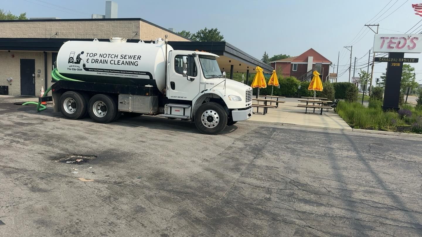 A white grease trap cleaning truck parked in front of 