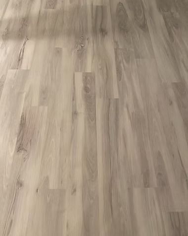 Close-up of light, gray-toned wood-look laminate flooring with natural grain and knot patterns.