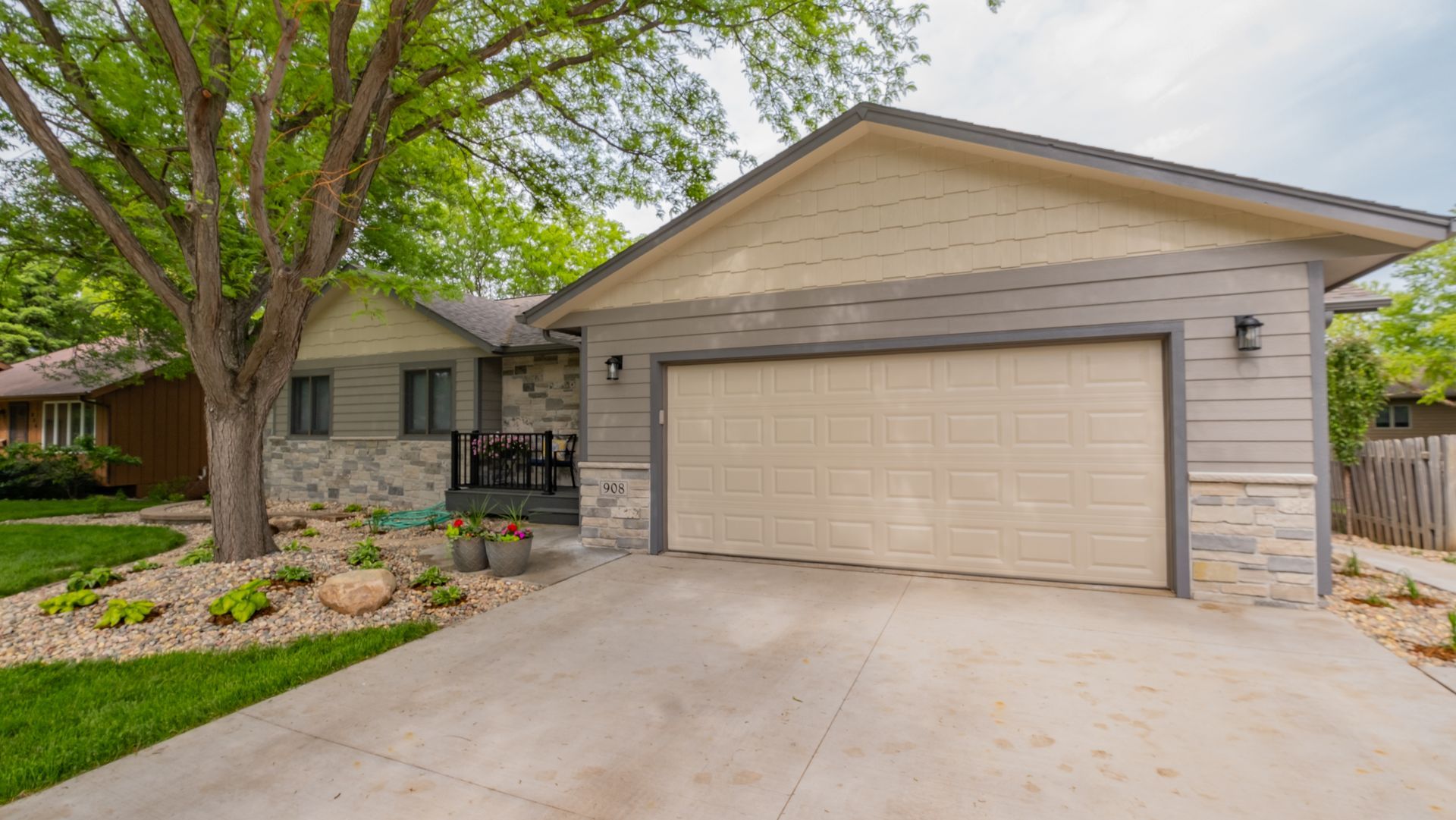 A house with a large garage door and a tree in front of it.