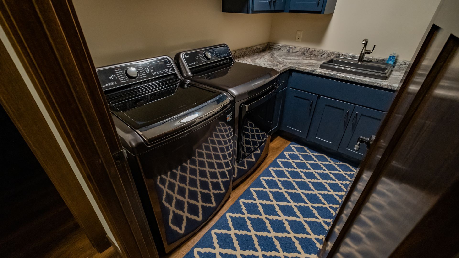 A laundry room with a washer and dryer and a blue rug.