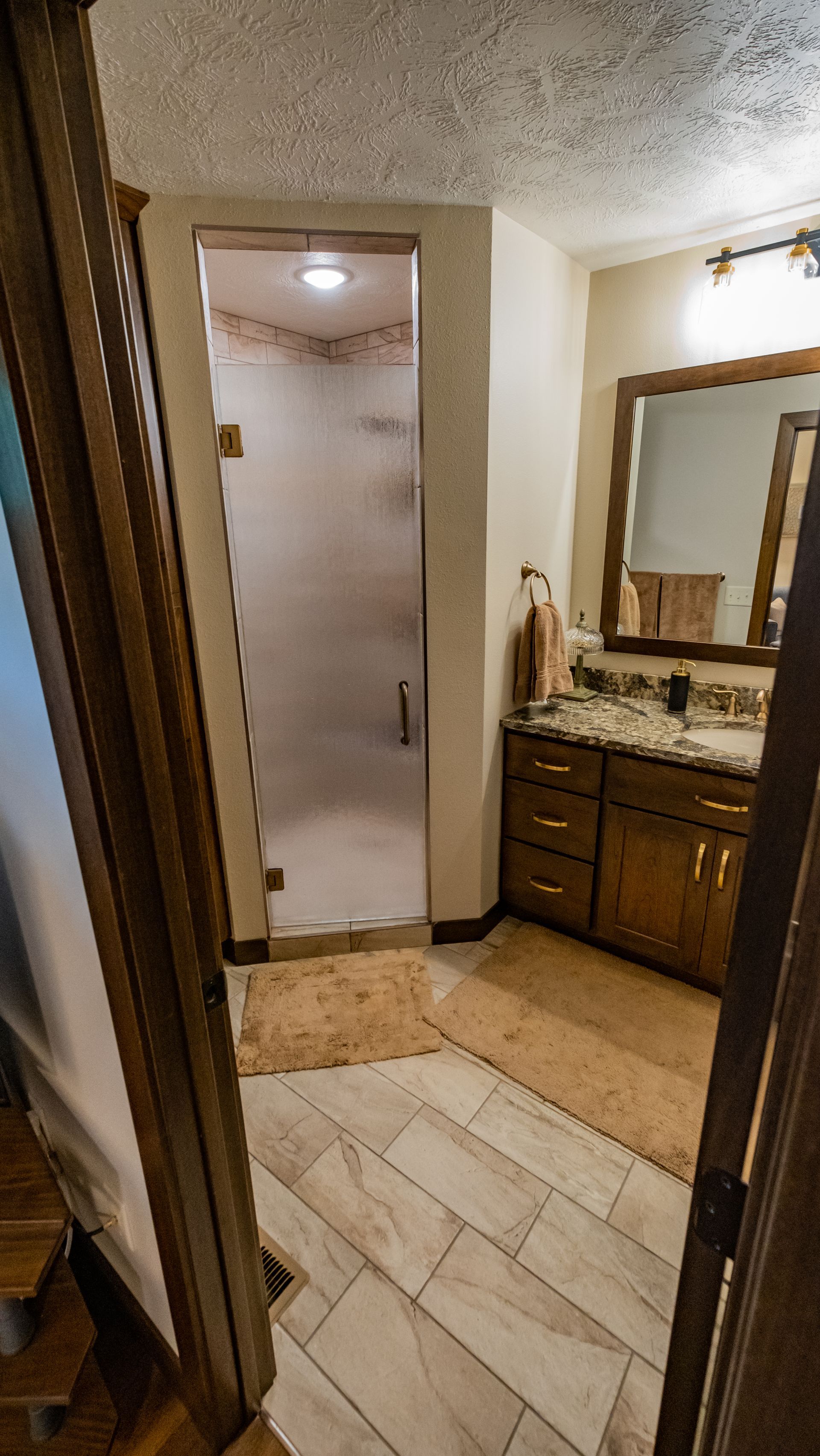 A bathroom with a walk in shower, sink and mirror.