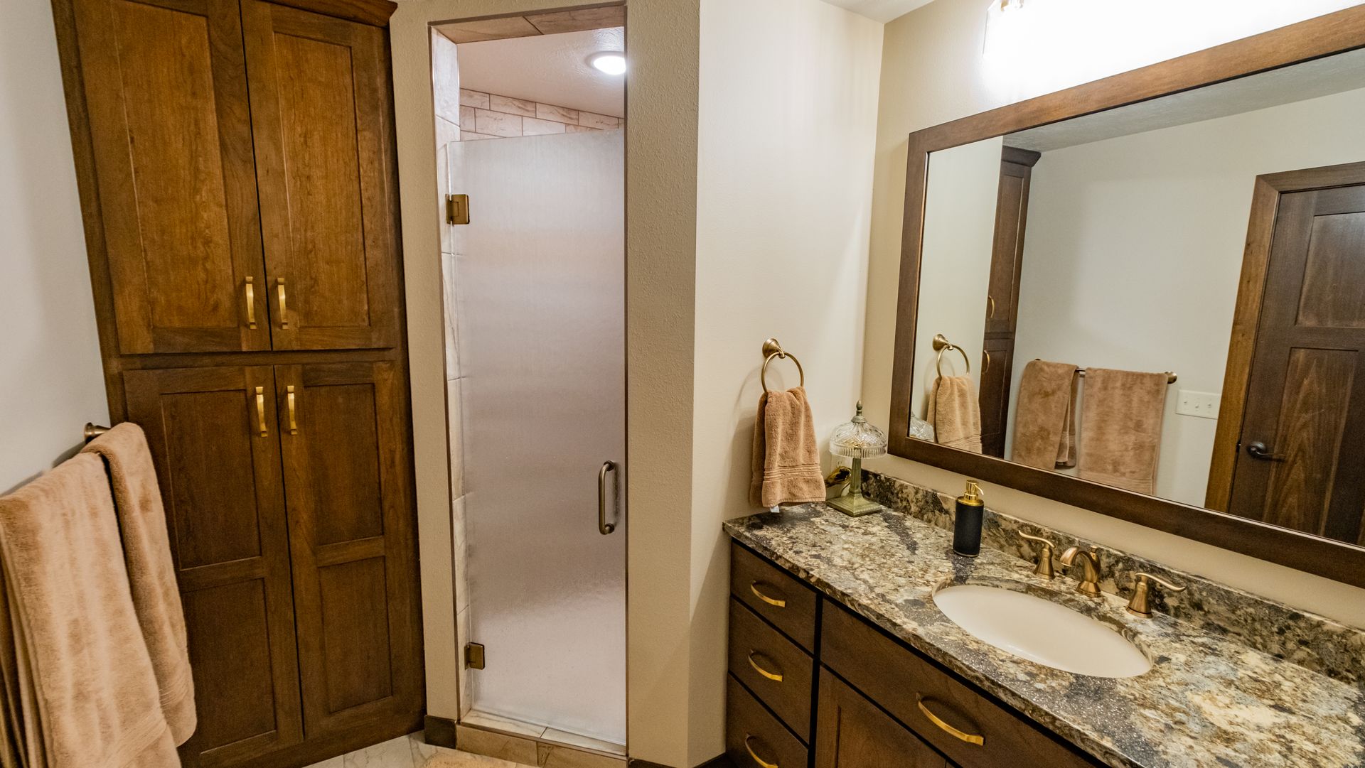 A bathroom with a sink, mirror and shower.